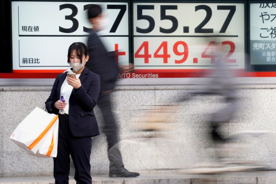 FILE - A person stands in front of an electronic stock board showing Japan's Nikkei 225 index at a securities firm on Dec. 27, 2023, in Tokyo. Asian shares were mixed in muted trading on Friday, Dec. 29, the last trading day of the year, with some regional markets logging solid gains in 2023 while many sagged.(AP Photo/Eugene Hoshiko, File)