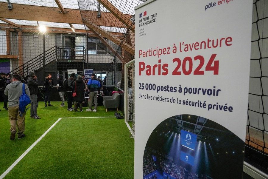 Job seekers line up to get the application papers during the Olympics jobs fair at sport center in Paris, Thursday, Dec. 14, 2023. Organizers urgently need many thousands of recruits for the huge security operation that will aim to keep athletes and spectators safe during the July 26-Aug. 11 Summer Games in the French capital that has been repeatedly hit by deadly extremist attacks. Placard reads, take part in the Paris 2024 adventure, 25,000 jobs to be filled. (AP Photo/Michel Euler)