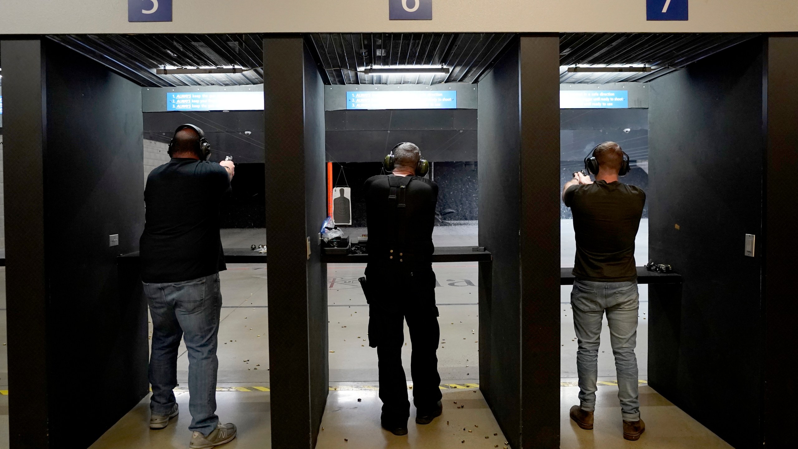 FILE - Gun owners fire their pistols at an indoor shooting range during a qualification course to renew their carry concealed handgun permits, July 1, 2022, at the Placer Sporting Club in Roseville, Calif. A California law that bans people from carrying firearms in most public places is taking effect on New Year's Day, even as a court case continues to challenge the law. (AP Photo/Rich Pedroncelli, File)