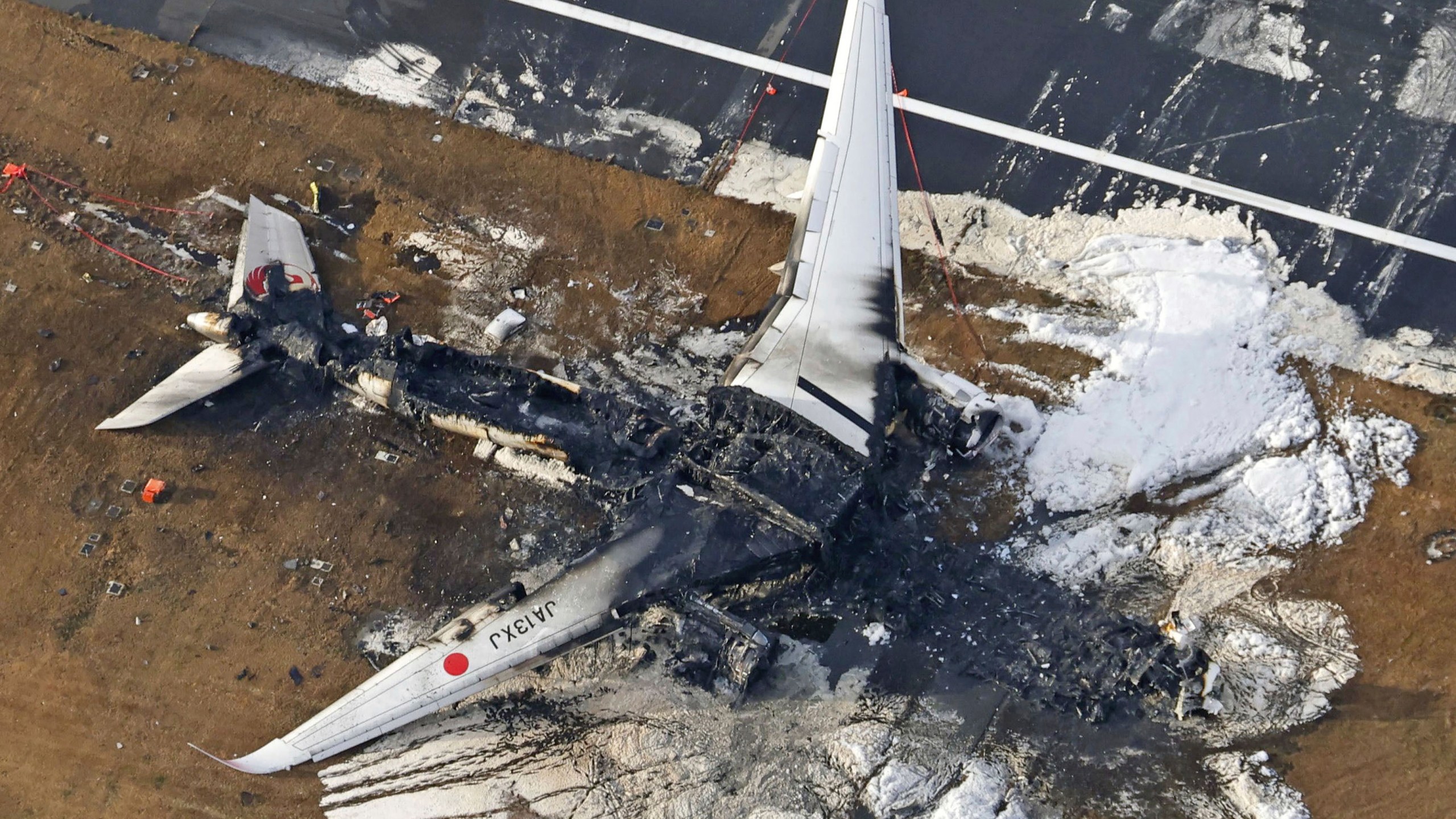 This aerial photo show the burn-out Japan Airlines plane at Haneda airport on Wednesday, Jan. 3, 2024, in Tokyo, Japan. The large passenger plane and a Japanese coast guard aircraft collided on the runway at Tokyo's Haneda Airport on Tuesday and burst into flames, killing several people aboard the coast guard plane, officials said. (Kyodo News via AP)