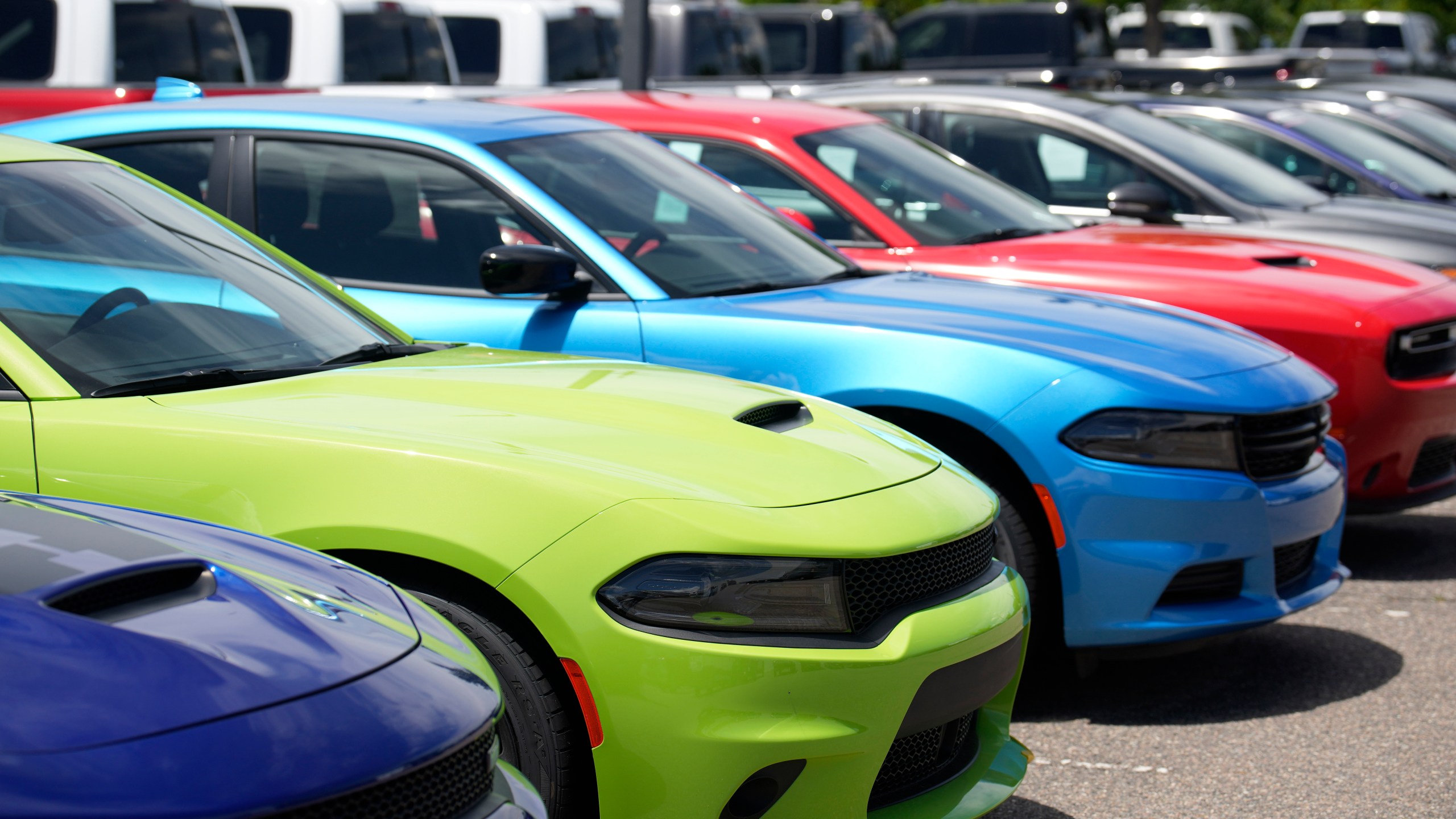 File - Unsold 2023 Charger sedans and Challenger hardtops sit at a Dodge dealership on June 18, 2023, in Littleton, Colo. Undeterred by high prices, rising interest rates, autoworker strikes and a computer chip shortage that slowed assembly lines, American consumers still bought 15.5 million new vehicles last year, 11% more than in 2022. (AP Photo/David Zalubowski, File)