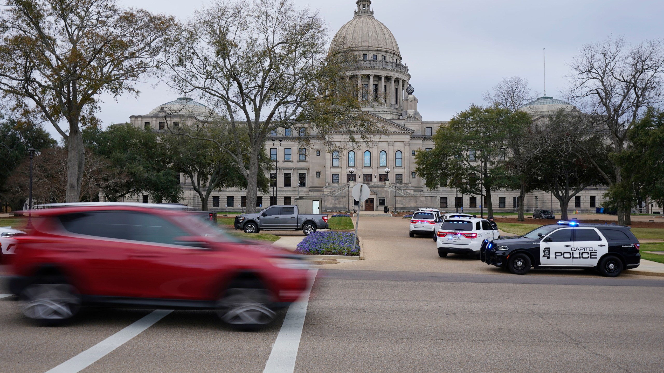 Traffic rolls past the Mississippi State Capitol in Jackson, Miss., as Capitol Police respond to a bomb threat within the building, Wednesday mornin, Jan. 3, 2024. The building was emptied, the grounds cleared of vehicles as officers investigated. (AP Photo/Rogelio V. Solis)