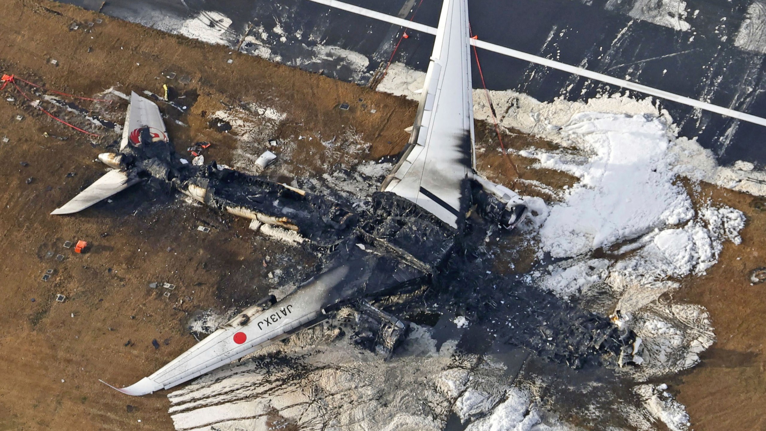 FILE - This aerial photo show the burn-out Japan Airlines plane at Haneda airport in Tokyo, on Jan. 3, 2024. The 379 passengers of Japan Airlines Flight JAL-516 didn't expect their plane to burst into flames just as it was about to touchdown at Tokyo’s Haneda airport Tuesday evening. A smaller coast guard Bombardier Dash-8 aircraft, preparing to take off to deliver urgent aid to quake-hit central Japan, was using the same runway when the two collided. The Associated Press collected accounts from witnesses, officials and transcripts of the traffic controls communication. (Kyodo News via AP, File)