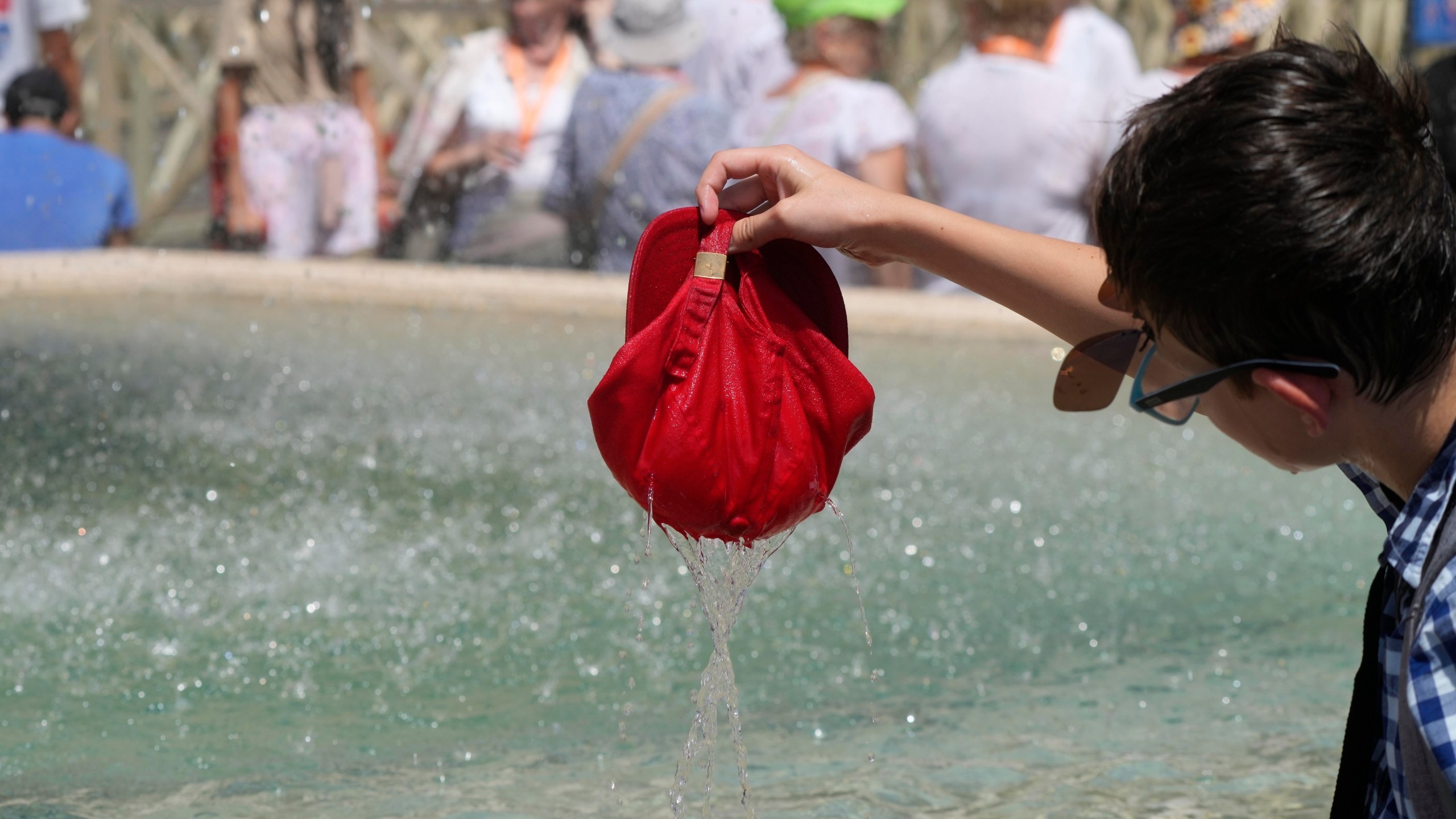 FILE - A child plunges his hat into a fountain on a hot day as he waits for the start of Pope Francis' Angelus prayer in St. Peter's Square at the Vatican, July 16, 2023. Earth last year shattered global annual heat records, the European climate agency said Tuesday, Jan. 9, 2024. (AP Photo/Gregorio Borgia, File)