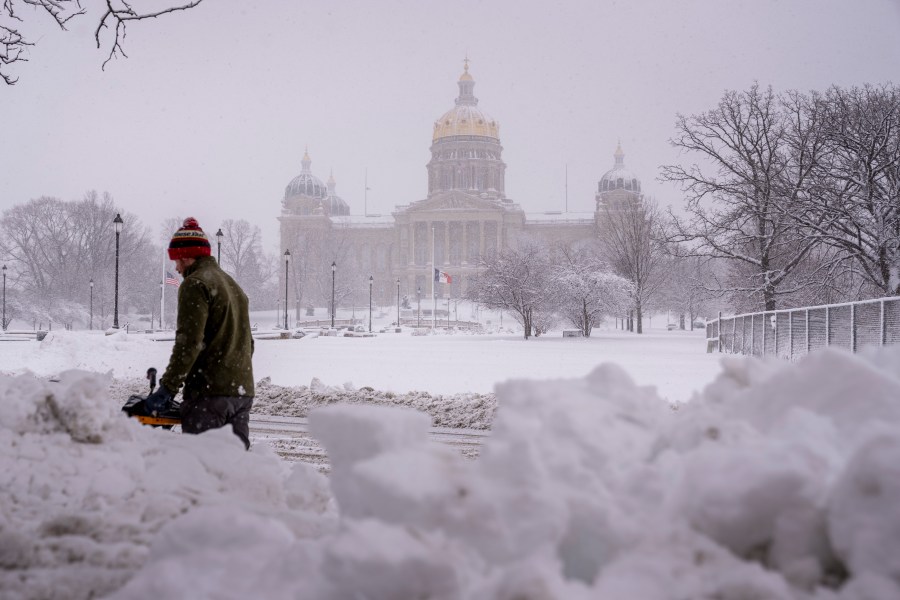 The Iowa State Capitol Building is visible as Spud Glaser of Carlisle, Iowa, plows the sidewalk in downtown Des Moines, Iowa, Tuesday, Jan. 9, 2024, as a winter snow storm hits the state. (AP Photo/Andrew Harnik)