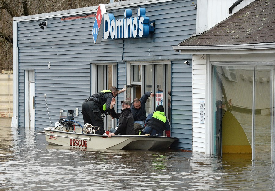 Mark Massey, second from left, and Keith Santor, second from right, are rescued Wednesday, Jan. 10, 2024, by the Yantic Fire Department during flooding in Norwich, Conn. (Dana Jensen/The Day via AP)