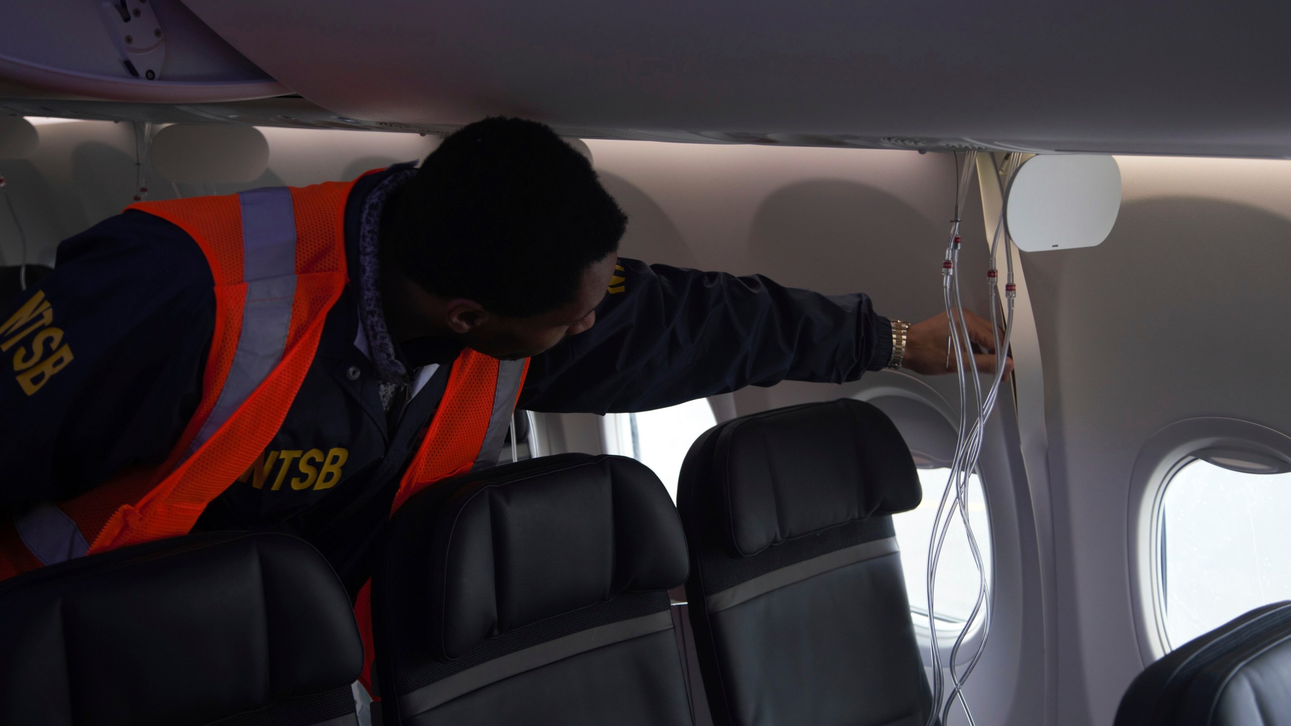 This image taken Sunday, Jan. 7, 2024, and released by the National Transportation Safety Board, an investigator examines the frame of a panel of Alaska Airlines Flight 1282 on a Boeing 737-9 MAX in Portland, Ore. Federal officials are investigating Boeing's oversight of production of a panel that blew off a jetliner in midflight last week. (NTSB via AP)