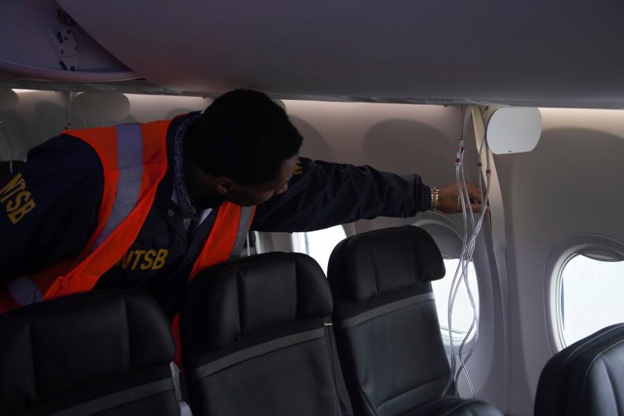 This image taken Sunday, Jan. 7, 2024, and released by the National Transportation Safety Board, an investigator examines the frame of a panel of Alaska Airlines Flight 1282 on a Boeing 737-9 MAX in Portland, Ore. Federal officials are investigating Boeing's oversight of production of a panel that blew off a jetliner in midflight last week. (NTSB via AP)