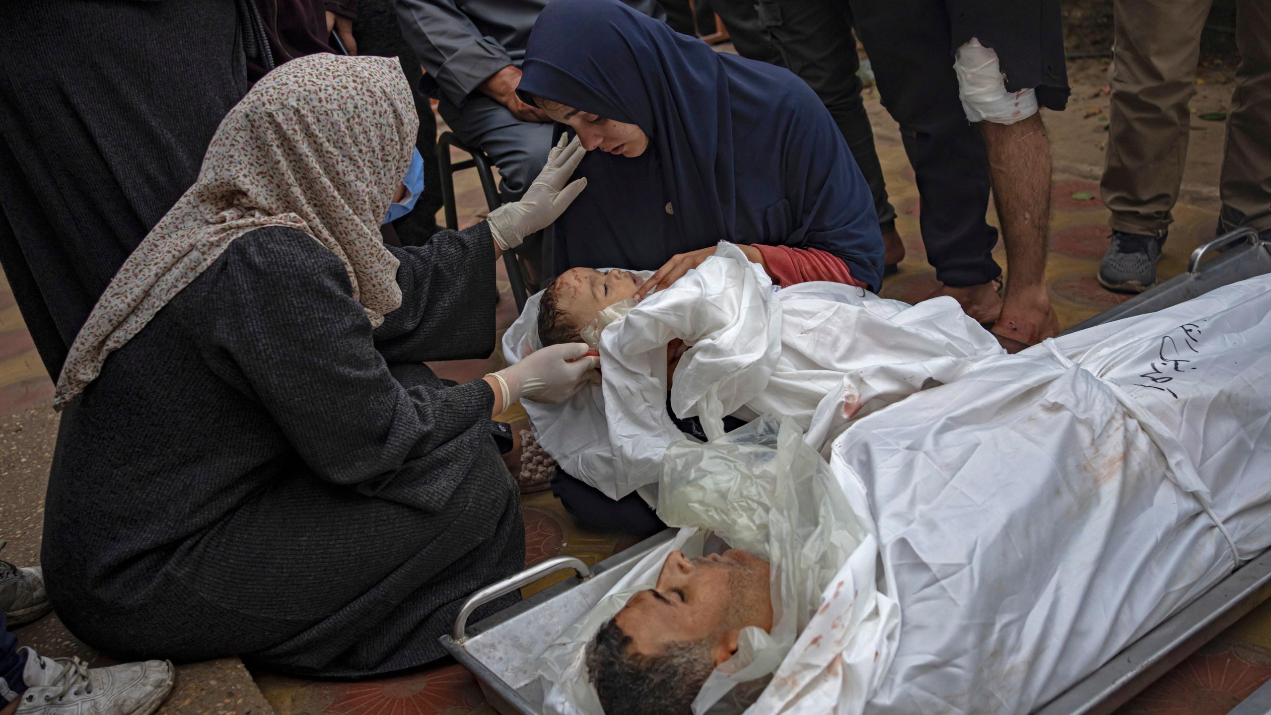 FILE - A Palestinian woman mourns her child and her husband killed in an Israeli army bombardment of the Gaza Strip, outside the hospital in Khan Younis, Tuesday Dec. 5, 2023. Now 100 days old, the latest Israel-Hamas war is by far the longest, bloodiest, and most destructive conflict between the bitter enemies. The fighting erupted on Oct. 7, 2023 when Hamas carried out a deadly attack in southern Israel. Since then, Israel has relentlessly pounded the Gaza Strip with airstrikes and a ground offensive that have wrought unprecedented destruction, flattening entire neighborhoods. (AP Photo/Fatima Shbair, File)