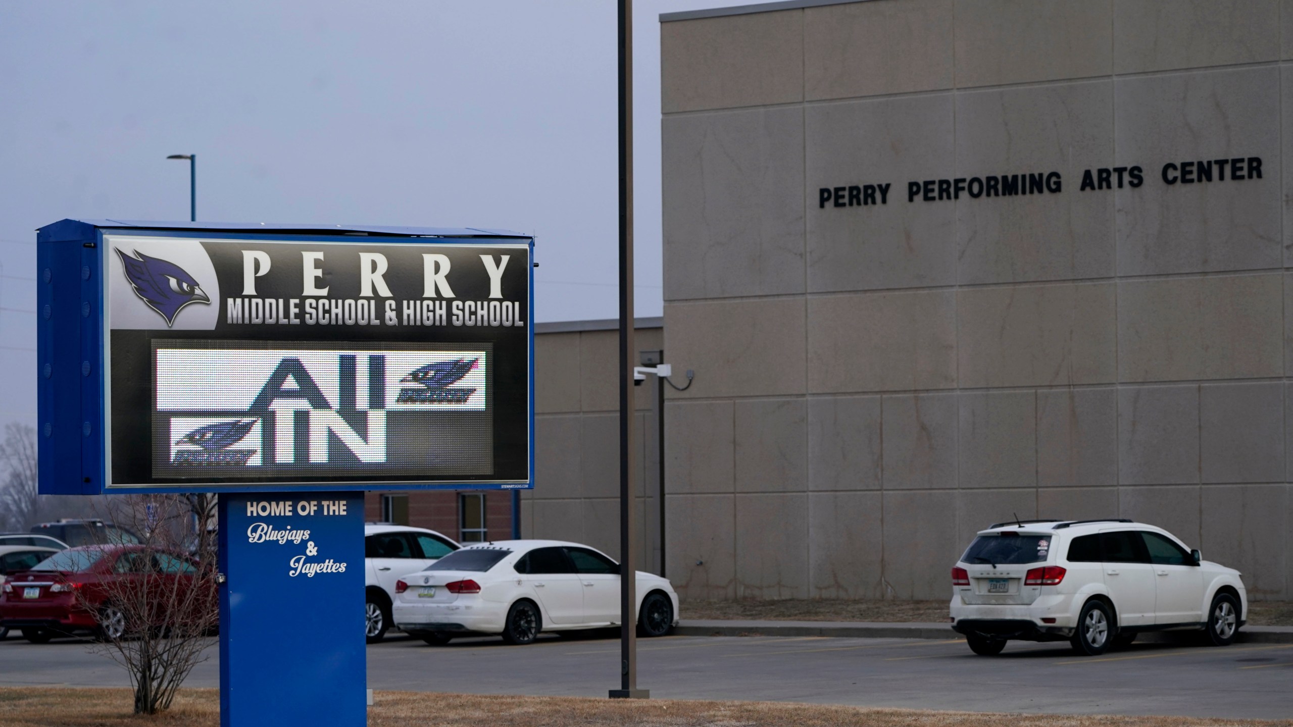 FILE - Vehicles are seen in a parking lot outside of Perry High School following a shooting at the school, Jan. 5, 2024, in Perry, Iowa. An Iowa principal who put himself in harm’s way to protect students during a school shooting earlier this month died Sunday, Jan. 14, 2024, a funeral home confirmed. Caldwell Parrish Funeral Home & Crematory confirmed the death of Perry High School Principal Dan Marburger after the family announced it on a GoFundMe page. (AP Photo/Charlie Neibergall, file)