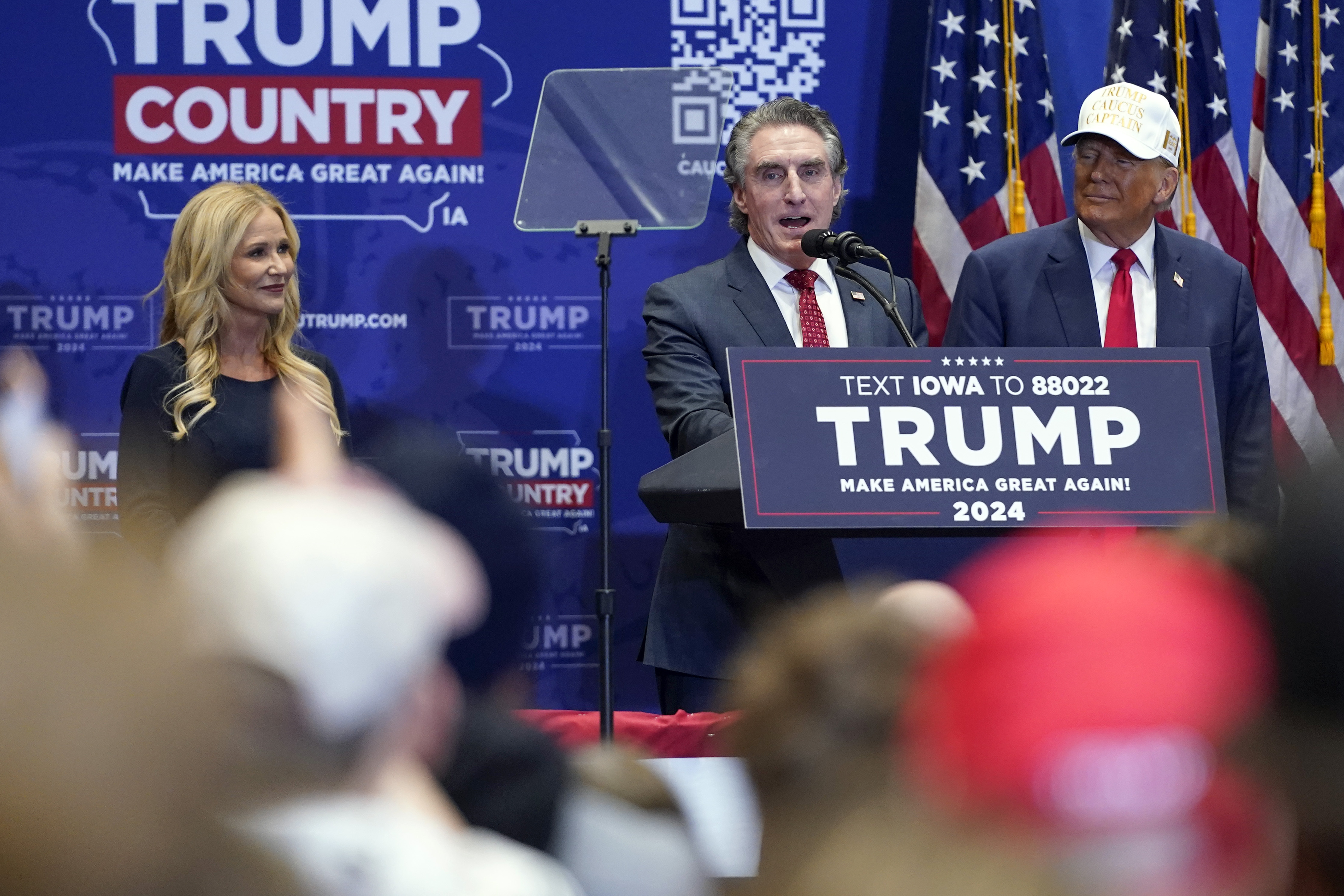 Republican presidential candidate former President Donald Trump listens as North Dakota Gov. Doug Burgum speaks at a rally at Simpson College in Indianola, Iowa, Sunday, Jan. 14, 2024. At left is Kathryn Burgum. (AP Photo/Andrew Harnik)