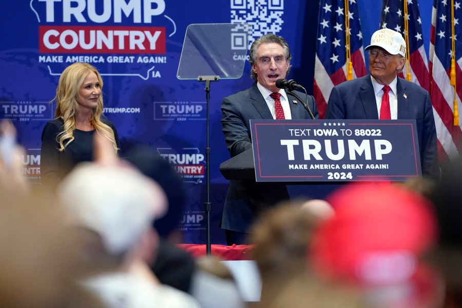 Republican presidential candidate former President Donald Trump listens as North Dakota Gov. Doug Burgum speaks at a rally at Simpson College in Indianola, Iowa, Sunday, Jan. 14, 2024. At left is Kathryn Burgum. (AP Photo/Andrew Harnik)