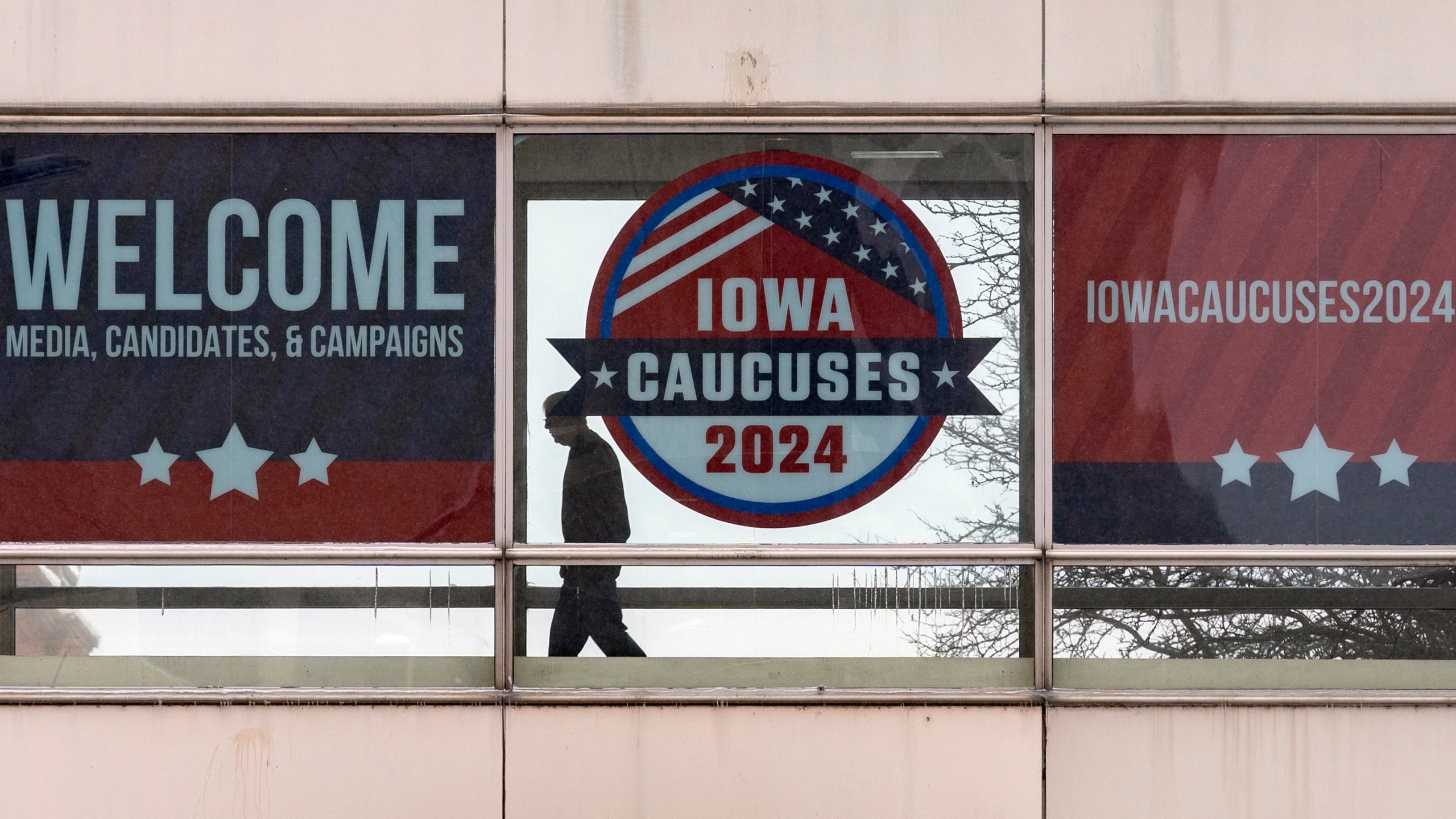 A man walks past a sign that reads "Iowa Caucuses 2024" in downtown Des Moines, Iowa, Saturday, Jan. 13, 2024. (AP Photo/Andrew Harnik)