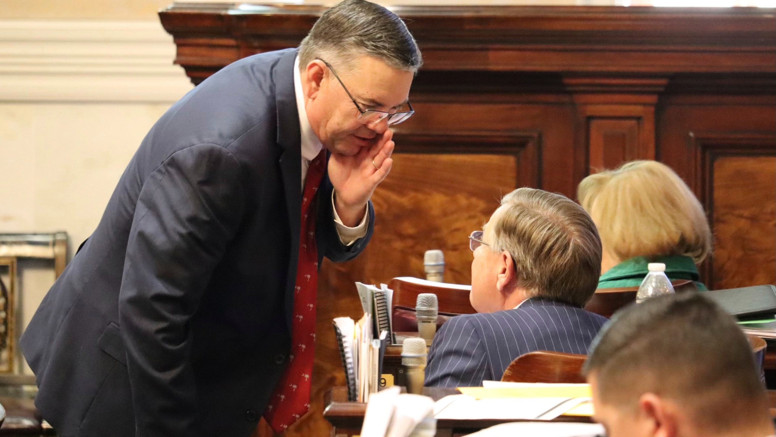 Republican South Carolina state Rep. John McCravy speaks with a colleague during a debate on gender-affirming care for minors , Wednesday, Jan. 17, 2024 in Columbia, S.C. The Republican-dominated South Carolina House is considering a bill that would bar health professionals from performing gender-transition surgeries, prescribing puberty-blocking drugs and overseeing hormone treatments for patients under 18 years old. (AP Photo/James Pollard)