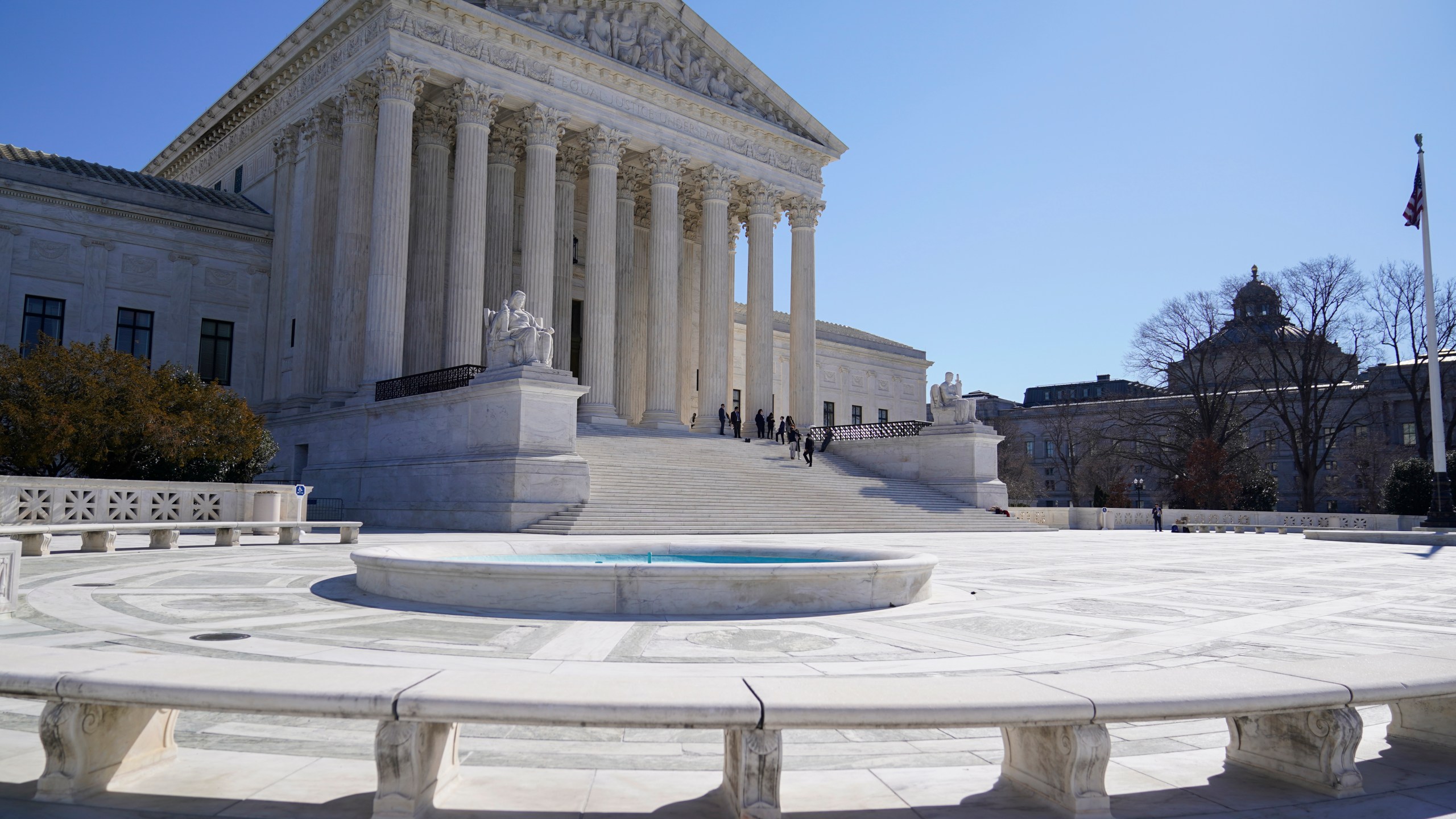 FILE - People stand on the steps of the U.S. Supreme Court, Feb.11, 2022, in Washington. The Supreme Court is taking up challenges by commercial fishermen to a fee requirement that could achieve a long-sought goal of business and conservative interests, limiting a wide range of government regulations. Billions of dollars are potentially at stake. (AP Photo/Mariam Zuhaib, File)