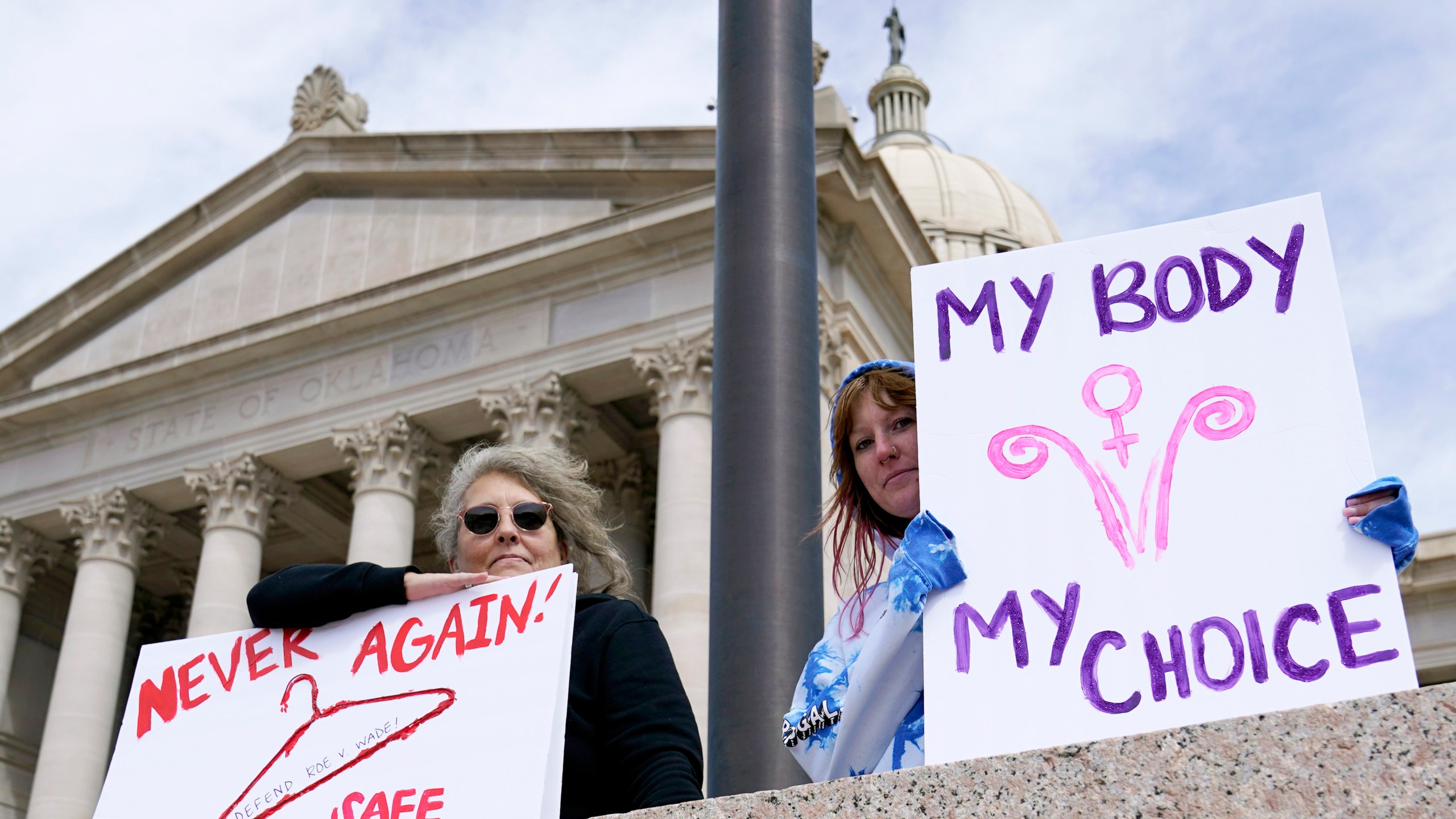 FILE - Dani Thayer, left, and Marina Lanae, right, both of Tulsa, Okla., hold pro-choice signs outside the state Capitol, Wednesday, April 13, 2022, in Oklahoma City. The U.S. Department of Health and Human Services said Friday, Jan 19, 2024, an Oklahoma hospital did not violate federal law when doctors told a woman with a nonviable pregnancy to wait in the parking lot until her condition worsened enough to qualify for an abortion under the state's strict ban. (AP Photo/Sue Ogrocki File)