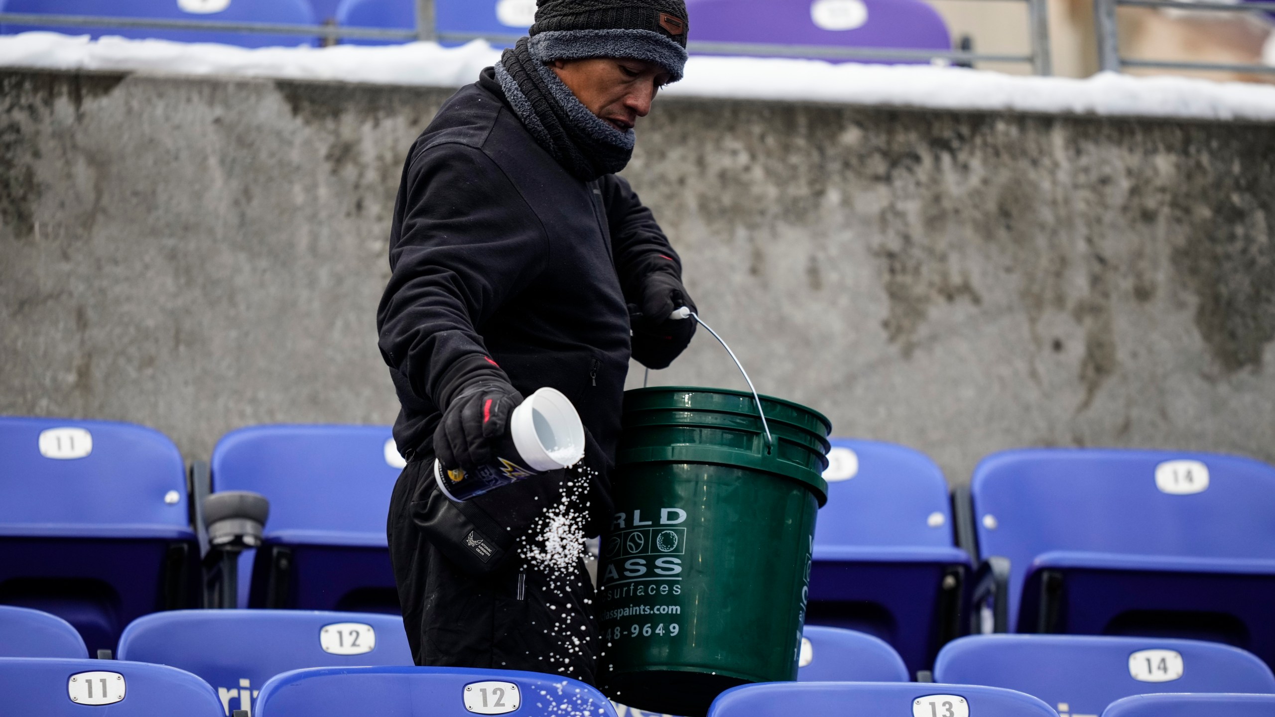 A stadium employee spreads salt in the stands before an NFL football AFC divisional playoff game between the Baltimore Ravens and the Houston Texans, Saturday, Jan. 20, 2024, in Baltimore. (AP Photo/Matt Slocum)