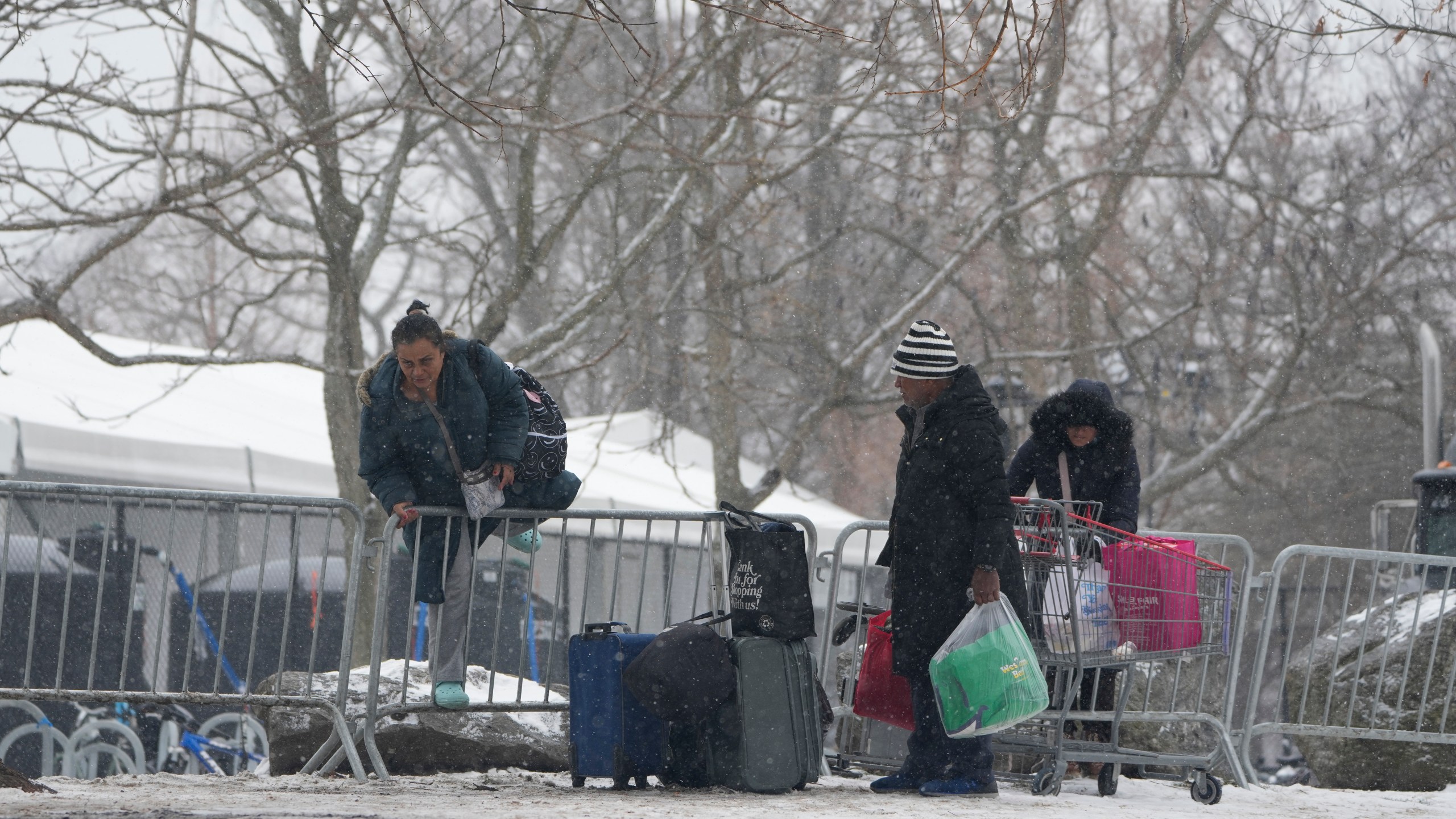 FILE - People hop a fence to get to a footbridge to Manhattan at a temporary shelter for migrants on Randall's Island in New York, Friday, Jan. 19, 2024. As New York City struggles to house an influx of immigrants, an unsanctioned tent community is growing outside the gates of the city's largest migrant shelter on Randall’s Island. New immigrants trying to earn a living have also set up a makeshift bazaar to sell coffee, snacks and other items. (AP Photo/Seth Wenig, File)