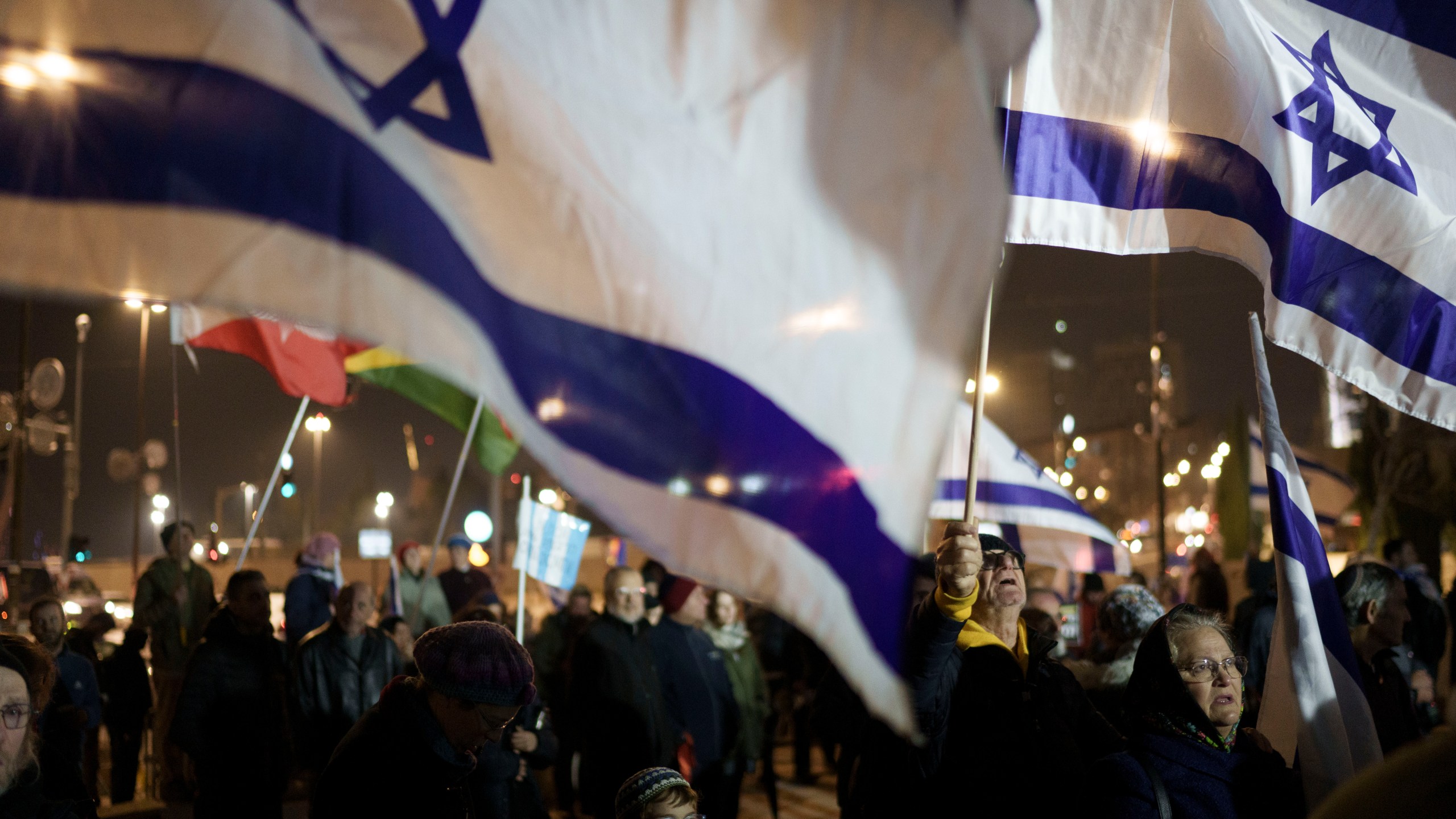 Holding up Israeli flags people take part in a protest against humanitarian aid entering Gaza and against the hostages exchange deal with Hamas, in Jerusalem, Israel, Thursday, Jan. 25, 2024. (AP Photo/Leo Correa)