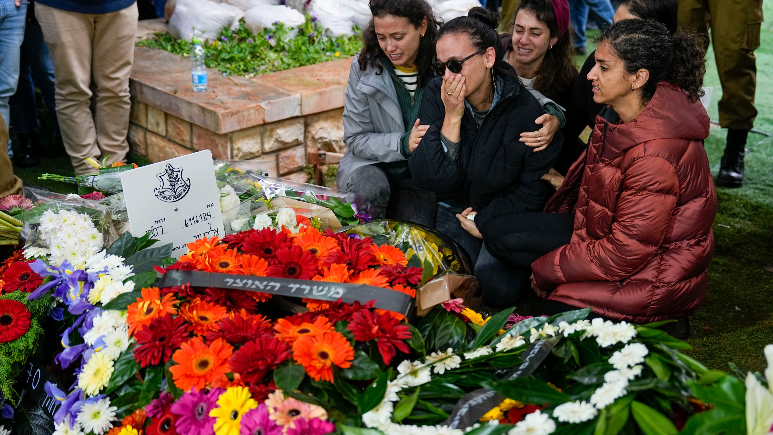 Raya, wife of Israeli reserve solider Sergeant major Eliran Yeger, mourns in grief around the grave during his funeral in Kiryat Shaul military cemetery in Tel Aviv, Israel, Sunday, Jan. 28, 2024. Yeger, 36, was killed during Israel's ground operation in the Gaza Strip, where the Israeli army has been battling Palestinian militants in the war ignited by Hamas' Oct. 7 attack into Israel. (AP Photo/Ariel Schalit)