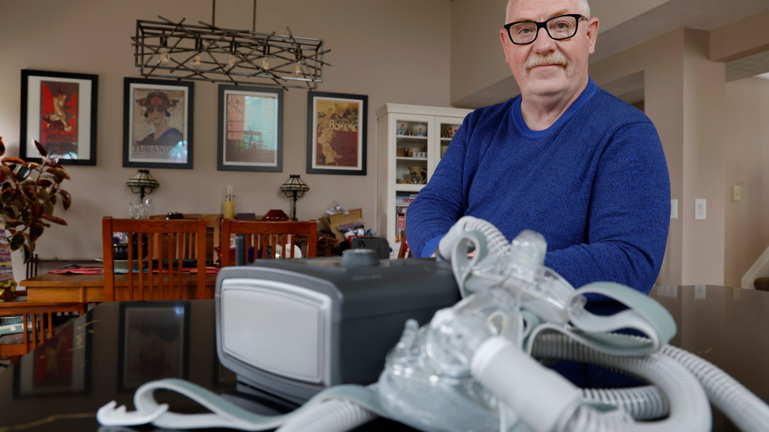 FILE - Jeffrey Reed, who experienced persistent sinus infections and two bouts of pneumonia while using a Philips CPAP machine, poses with the device at his home, Oct. 20, 2022, in Marysville, Ohio. On Monday, Jan. 29, 2024, Philips, the company behind a global recall of sleep apnea machines, said it will stop selling the devices in the U.S., under a tentative agreement with regulators that could cost the company nearly $400 million. (AP Photo/Jay LaPrete, File)