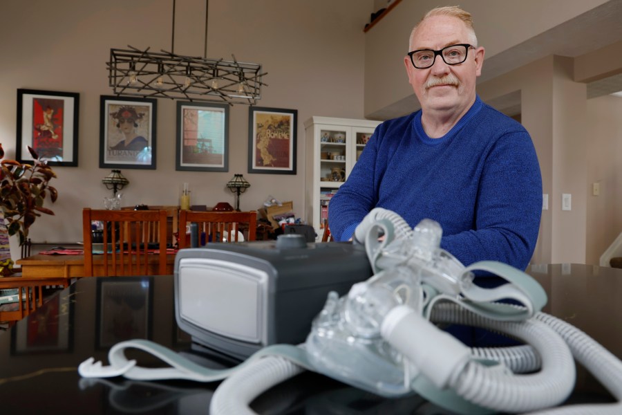 FILE - Jeffrey Reed, who experienced persistent sinus infections and two bouts of pneumonia while using a Philips CPAP machine, poses with the device at his home, Oct. 20, 2022, in Marysville, Ohio. On Monday, Jan. 29, 2024, Philips, the company behind a global recall of sleep apnea machines, said it will stop selling the devices in the U.S., under a tentative agreement with regulators that could cost the company nearly $400 million. (AP Photo/Jay LaPrete, File)