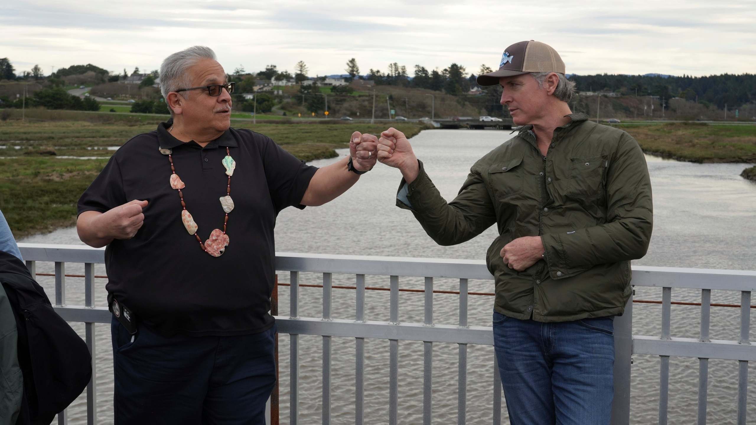 California Gov. Gavin Newsom fist-bumps Wiyot Tribal Chair Ted Hernandez at the Elk River where they were touring a salmon restoration project in Eureka, Calif., Monday, Jan. 29, 2024. (AP Photo/Terry Chea)