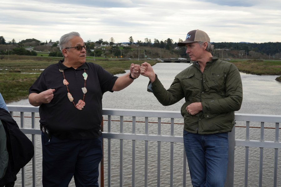 California Gov. Gavin Newsom fist-bumps Wiyot Tribal Chair Ted Hernandez at the Elk River where they were touring a salmon restoration project in Eureka, Calif., Monday, Jan. 29, 2024. (AP Photo/Terry Chea)