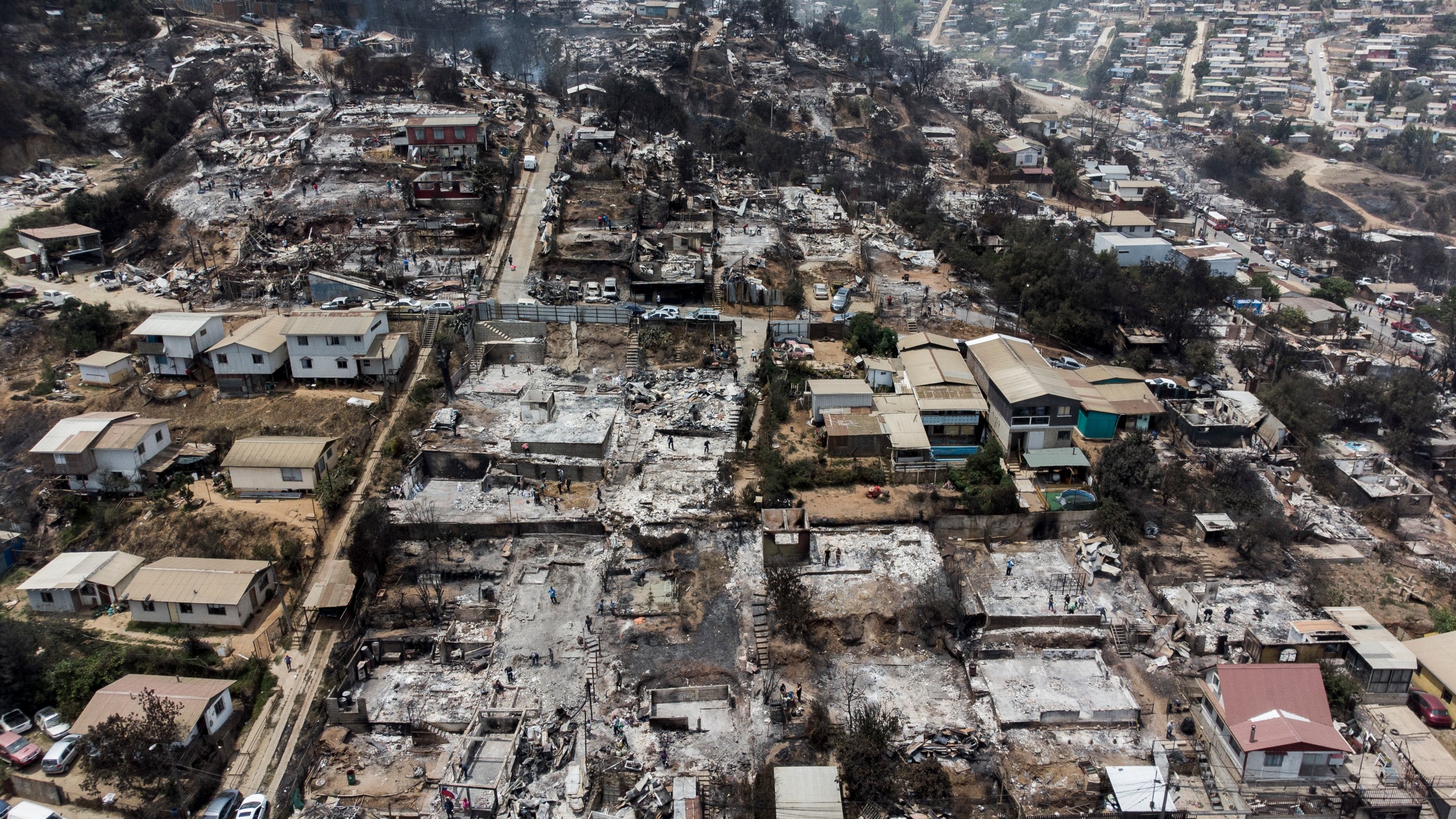 Locals clean the rubble of burnt-out houses after forest fires reached their neighborhood in Vina del Mar, Chile, Sunday, Feb. 4, 2024. (AP Photo/Cristobal Basaure)