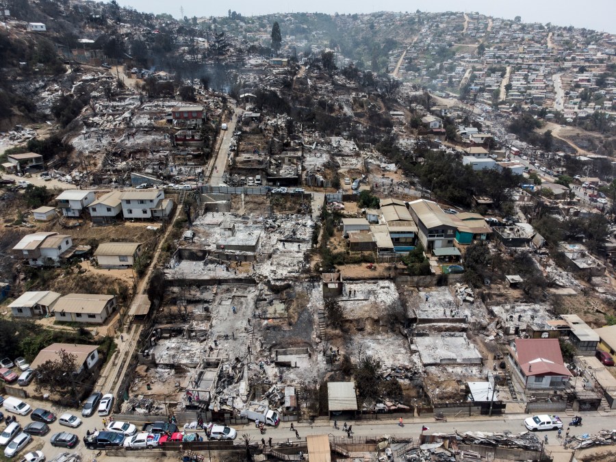 Locals clean the rubble of burnt-out houses after forest fires reached their neighborhood in Vina del Mar, Chile, Sunday, Feb. 4, 2024. (AP Photo/Cristobal Basaure)