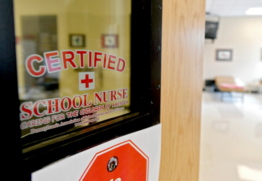 This photo taken Aug. 15, 2016, shows the front of the Bellefonte Area School District certified school nurses office. Schools are confronting soaring absence rates. Some are calling for parents to send their children to class even if they are not feeling 100% well. During the pandemic, schools urged parents and children to stay home at any sign of illness. Now that the COVID-19 emergency has ended, guidance on when to keep children home varies widely. The American Academy of Pediatrics recommends staying home with fever, vomiting or diarrhea, or when students “are not well enough to participate in class.” But many districts go far beyond that, delineating a dizzying array of symptoms they say should rule out attendance. (Abby Drey/Centre Daily Times via AP, file)