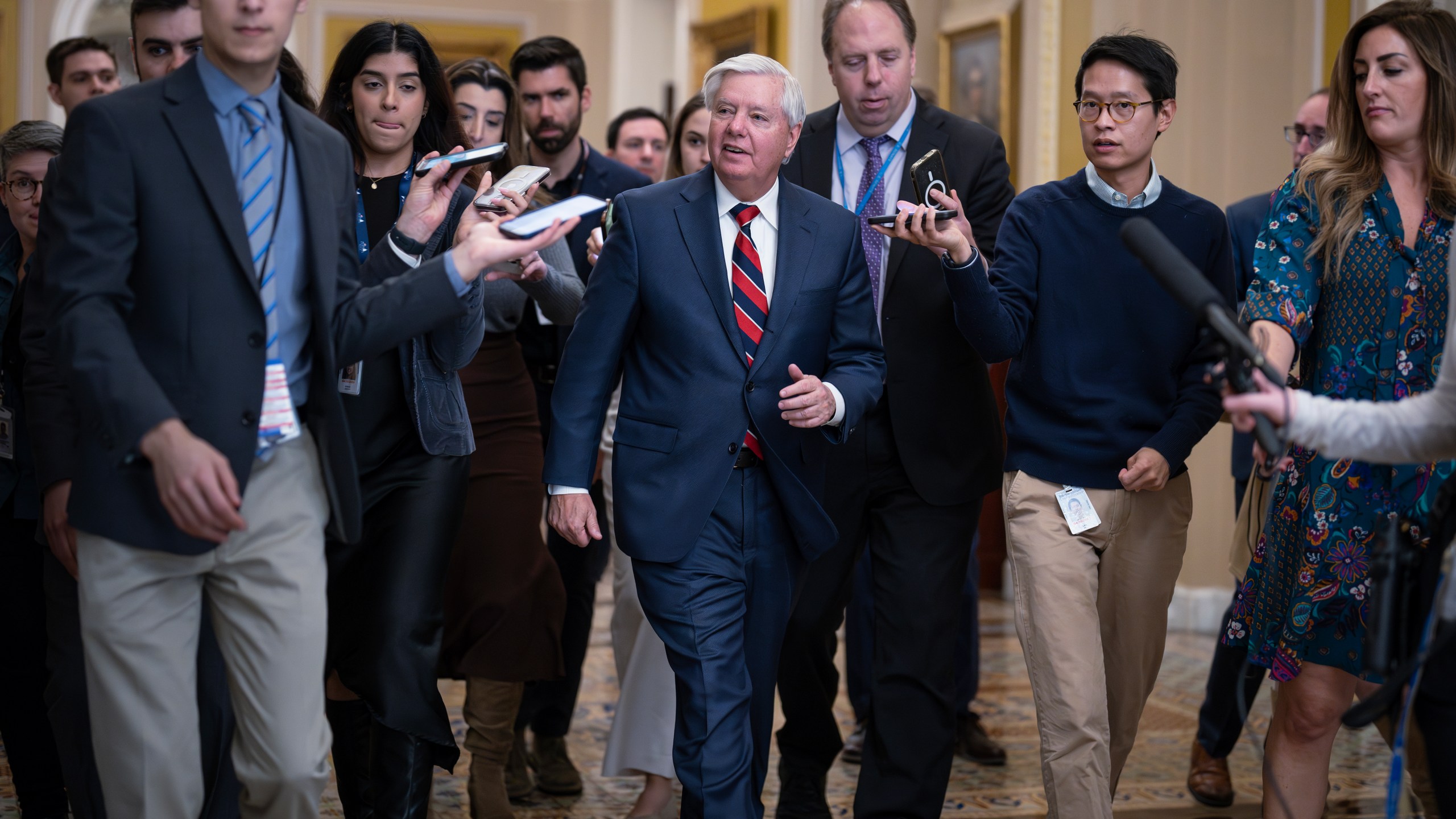 With reporters seeking comment, Sen. Lindsey Graham, R-S.C., walks to the chamber during a test vote to begin debate on a border security bill, at the Capitol in Washington, Wednesday, Feb. 7, 2024. (AP Photo/J. Scott Applewhite)