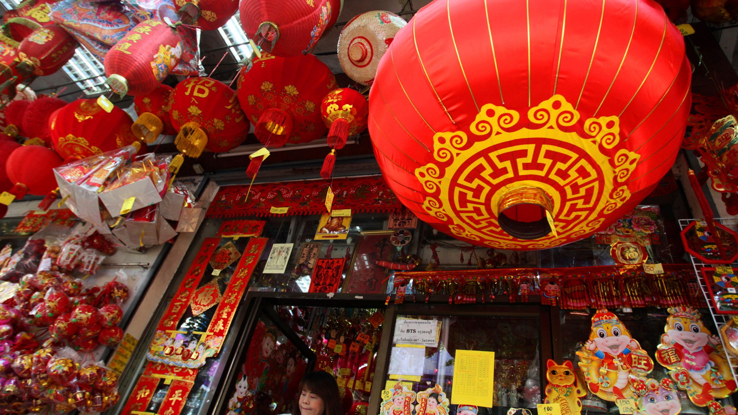 FILE - This Feb. 6, 2013 file photo shows a woman walking out a shop selling seasonal items ahead of Chinese New Year in Chinatown in Bangkok, Thailand. In many Asian cultures, the Lunar New Year is a celebration marking the arrival of spring and the start of a new year on the lunisolar calendar. It's the most important holiday in China where it's observed as the Spring Festival. It's also celebrated in South Korea, Vietnam and diaspora communities around the world. (AP Photo/Sakchai Lalit, File)