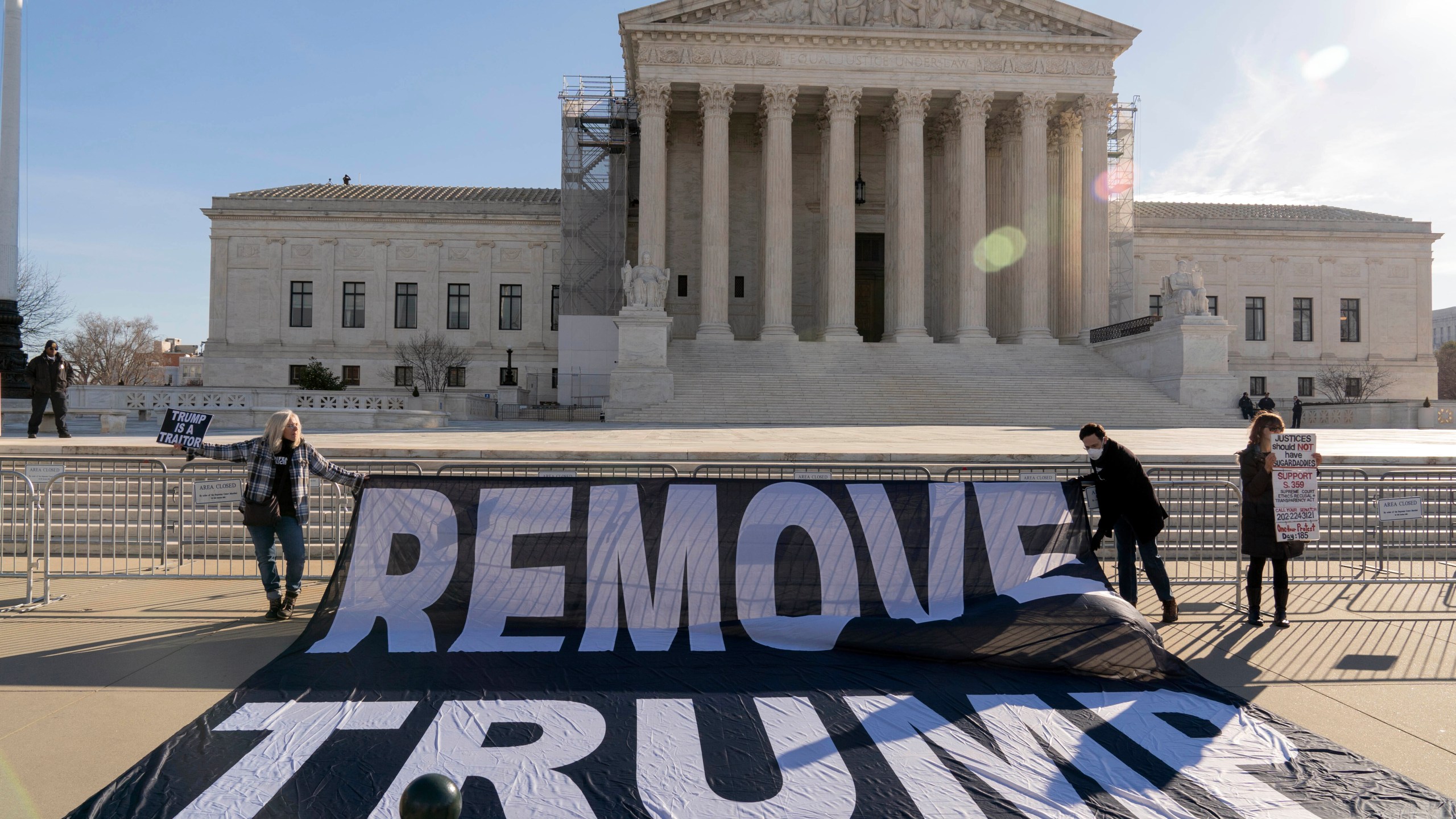 Demonstrators hold a banner outside of the U.S. Supreme Court, Thursday, Feb. 8, 2024, in Washington. The U.S. Supreme Court on Thursday will take up a historic case that could decide whether Donald Trump is ineligible for the 2024 ballot under Section 3 of the 14th Amendment. (AP Photo/Jose Luis Magana)