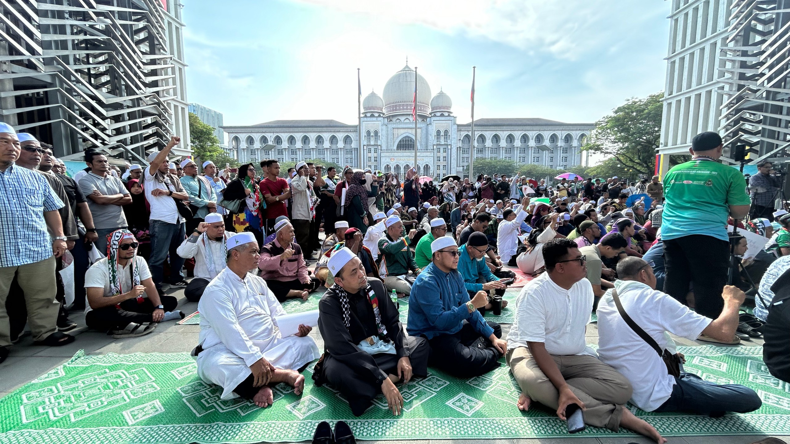 Members of the Pan-Malaysian Islamic Party wait outside the Palace of Justice, background, as they await the Federal Court's decision on Kelantan state's sharia law criminal enactment, in Putrajaya, Malaysia Friday, Feb. 9, 2024. Malaysia's top court Friday struck down over a dozen Shariah-based state laws, saying they encroached on federal authority, a decision denounced by Islamists who fear it could undermine religious courts across the country.(AP Photo)