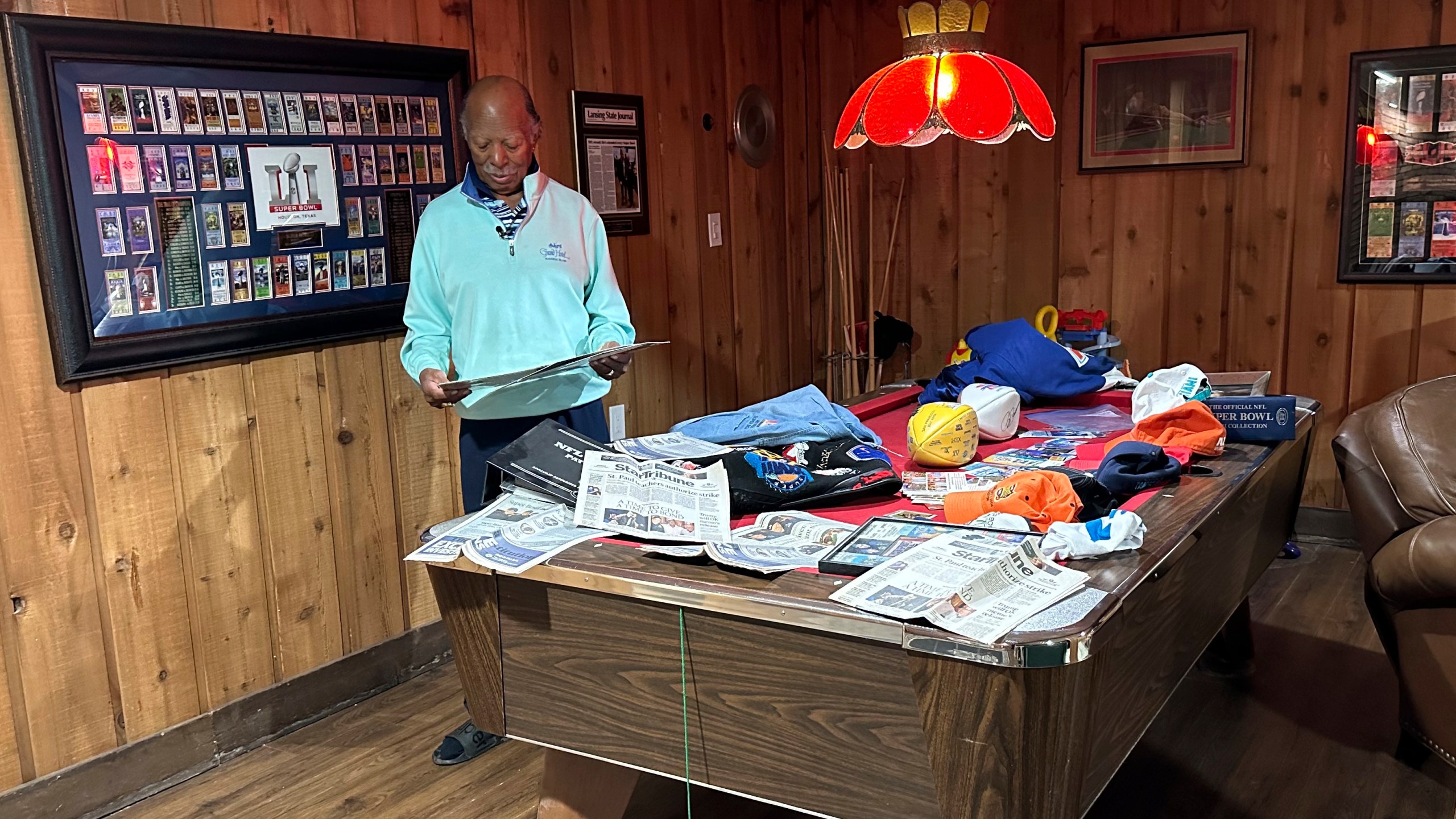 Gregory Eaton looks at some Super Bowl memorabilia at his home, Tuesday, Jan. 30, 2024 in Lansing, Mich. Eaton is a member of the exclusive "never missed a Super Bowl" club. He and two friends, all in their 80s, plan to be in Las Vegas on Sunday for Super Bowl 58. (AP Photo/Mike Householder)