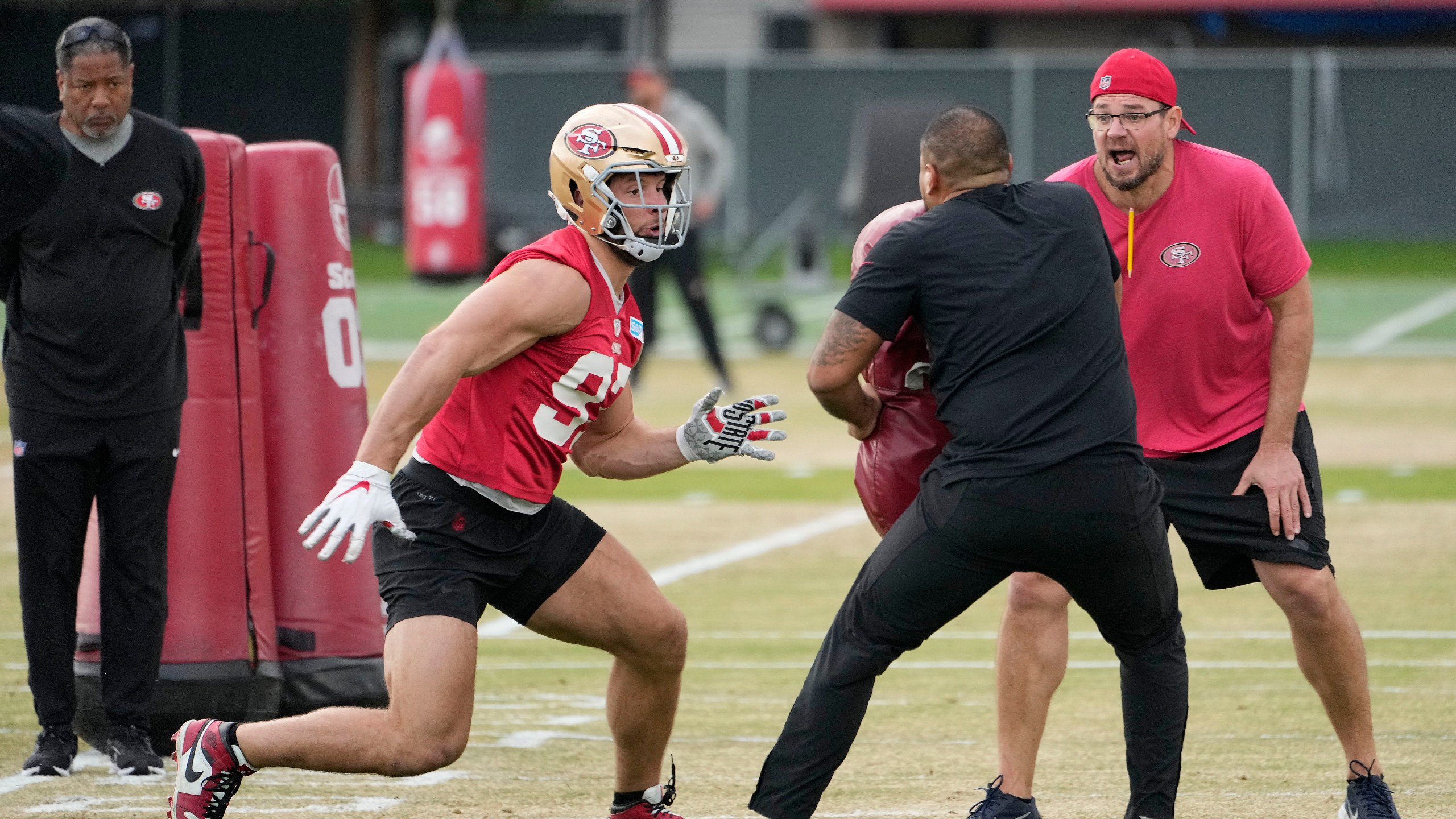 San Francisco 49ers defensive end Nick Bosa (97) runs a drill as defensive coordinator Steve Wilks, left, and defensive line coach Kris Kocurek, right, look on during practice at the team's NFL football training facility in Santa Clara, Calif., Thursday, Feb. 1, 2024. The 49ers will face the Kansas City Chiefs in Super Bowl 58. (AP Photo/Tony Avelar)