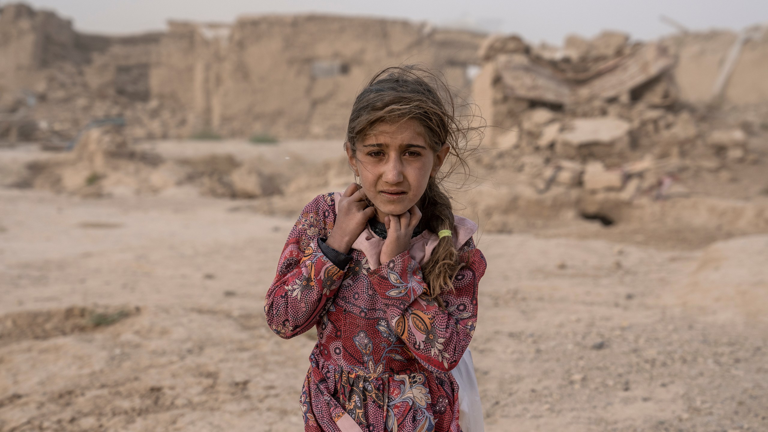 FILE - An Afghan girl carries donated aid to her tent, while she is scared from the fierce sandstorm, after an earthquake in Zenda Jan district in Herat province, western of Afghanistan, Oct. 12, 2023. Human Rights Watch said Monday, Feb. 12, 2024 that Afghanistan’s public health system has been hit hard following a sharp reduction in foreign assistance, coupled with serious Taliban abuses against women and girls, jeopardizing the right to healthcare of millions of Afghans. (AP Photo/Ebrahim Noroozi, File)