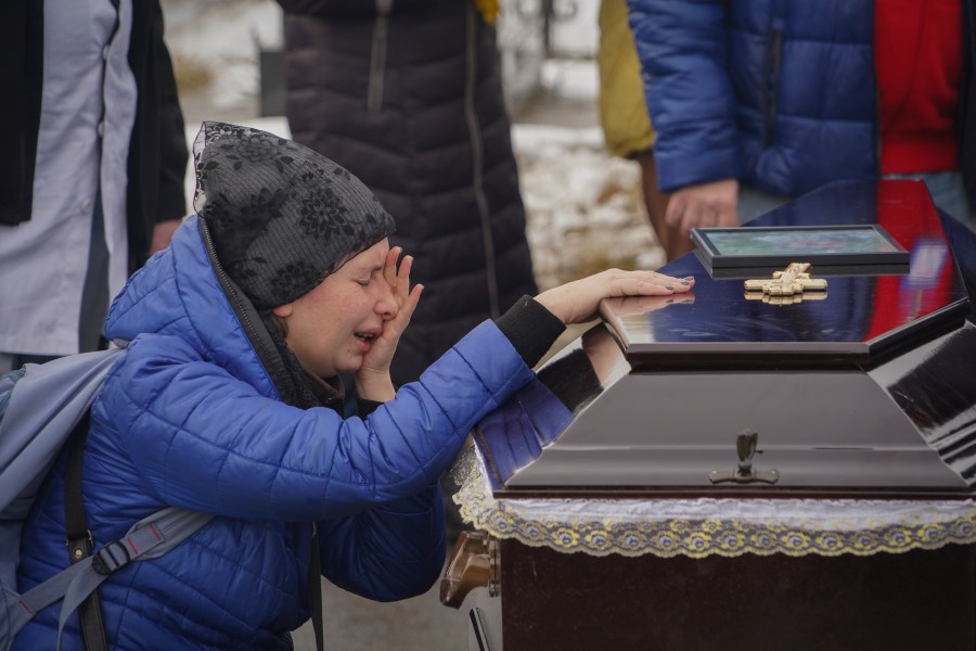 People mourn over the coffins of a family killed in a fire when Russian drone hit their home in residential neighbourhood in Kharkiv, Ukraine, Monday, Feb. 12, 2024. Seven people including three children were killed on Saturday in the Russian drone attack. (AP Photo/Andrii Marienko)