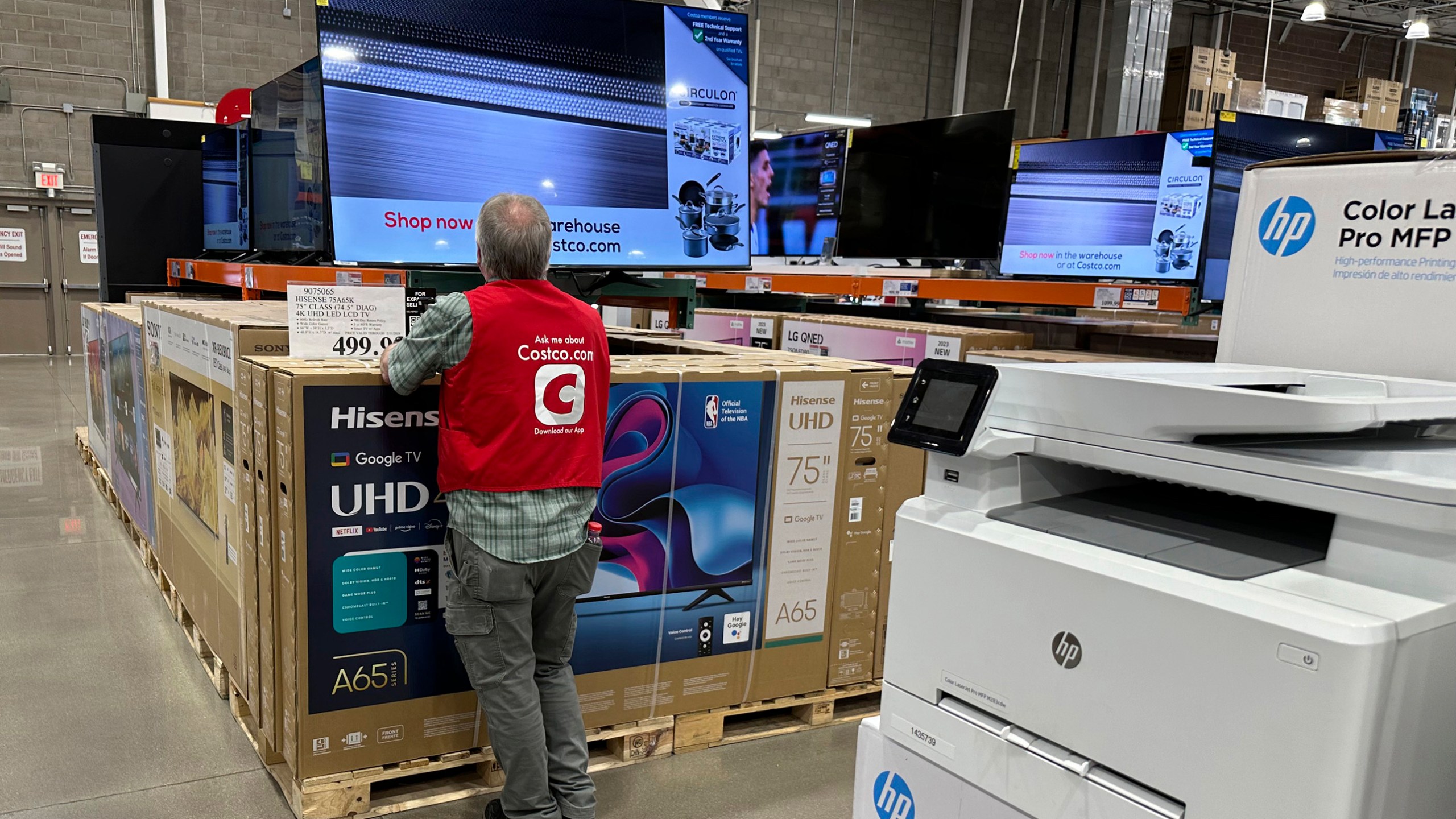 An associate checks over a big-screen television on display in a Costco warehouse Tuesday, Feb. 6, 2024, in Colorado Springs, Colo. (AP Photo/David Zalubowski)