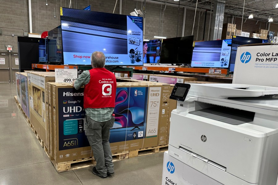 An associate checks over a big-screen television on display in a Costco warehouse Tuesday, Feb. 6, 2024, in Colorado Springs, Colo. (AP Photo/David Zalubowski)