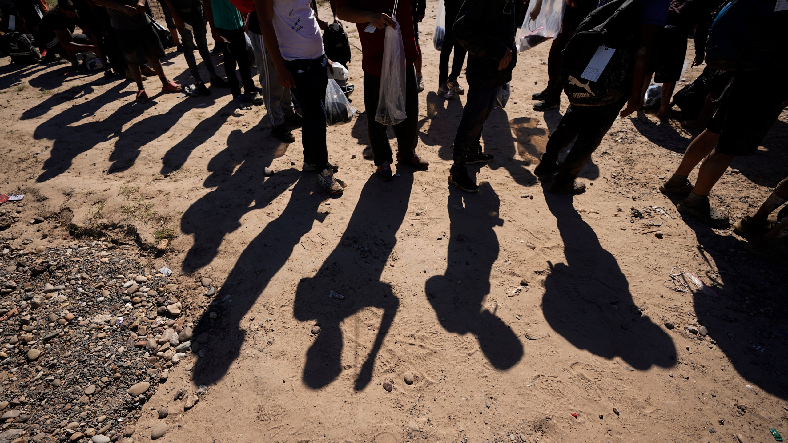 FILE - Migrants wait to be processed by the U.S. Customs and Border Patrol after they crossed the Rio Grande and entered the U.S. from Mexico, Oct. 19, 2023, in Eagle Pass, Texas. A federal judge on Thursday, Feb. 15, 2024, will consider whether Texas can enforce a new law that gives police broad authority to arrest migrants who are accused of entering the U.S. illegally and empowers local judges to order them out of the country. (AP Photo/Eric Gay, File)