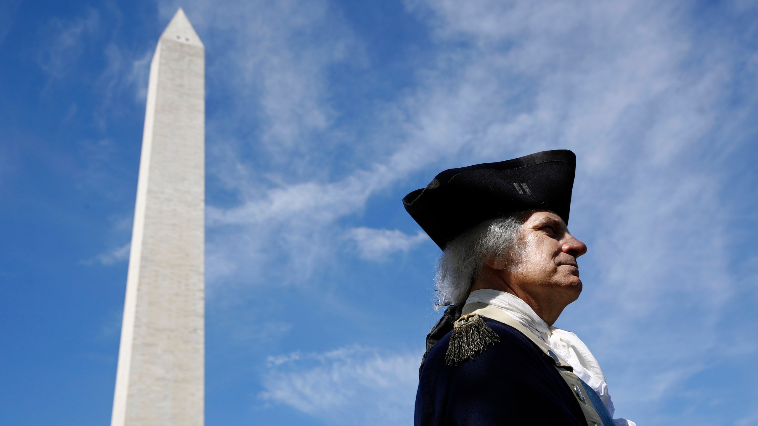 FILE - John Lopes, playing the part of President George Washington, stands near the Washington Monument following a ribbon-cutting ceremony with first lady Melania Trump to re-open the monument, Thursday, Sept. 19, 2019, in Washington. Like the other Founding Fathers, George Washington was uneasy about the idea of publicly celebrating his life. He was the first leader of a new republic — not a tyrant. (AP Photo/Patrick Semansky, File)