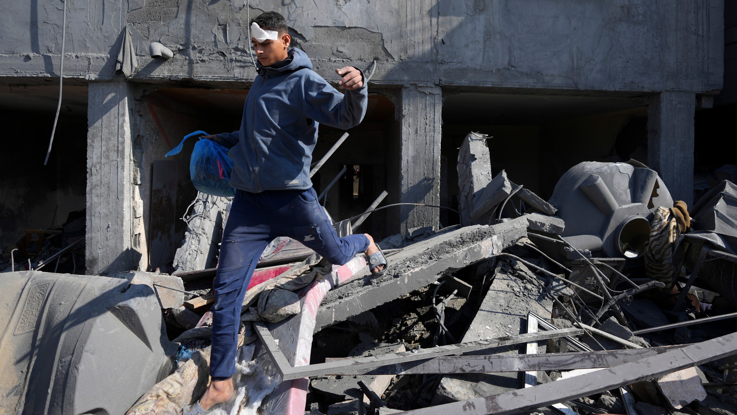 A Palestinian walks through the rubble of the Khatab family building after an Israeli airstrike in Deir al Balah, Gaza Strip, Wednesday, Feb. 21, 2024. (AP Photo/Adel Hana)