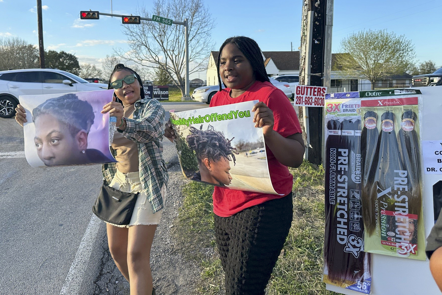 Shan'Terrius Sly-Brown, 16, left, and Shaniya Wade-Red, 15, hold signs during a protest outside of the home of Barbers Hill Independent School District superintendent Greg Poole, Wednesday, Feb. 21, 2024 in Baytown, Texas. The teenagers traveled from Holmes County in Mississippi to participate in the protest and attend a Thursday bench trial for Darryl George, a student who was punished over his hairstyle. George, who is Black and has been kept out of his regular classes since Aug. 31, 2023, says his hairstyle is protected by a new state law that prohibits race-based hair discrimination. (AP Photo/Juan Lozano)