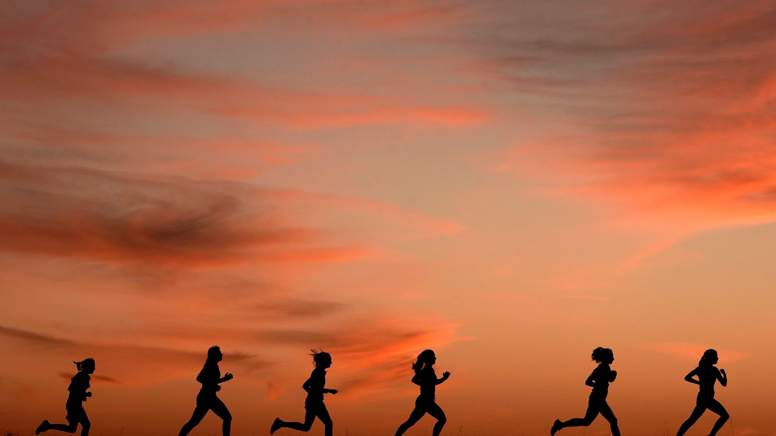 FILE - High school students run at sunset as they practice for the track and field season Monday, Feb. 28, 2022, in Shawnee, Kan. The killing of a 22-year-old nursing student has once again put the spotlight on dangers faced by female athletes who practice sports alone. (AP Photo/Charlie Riedel, File)