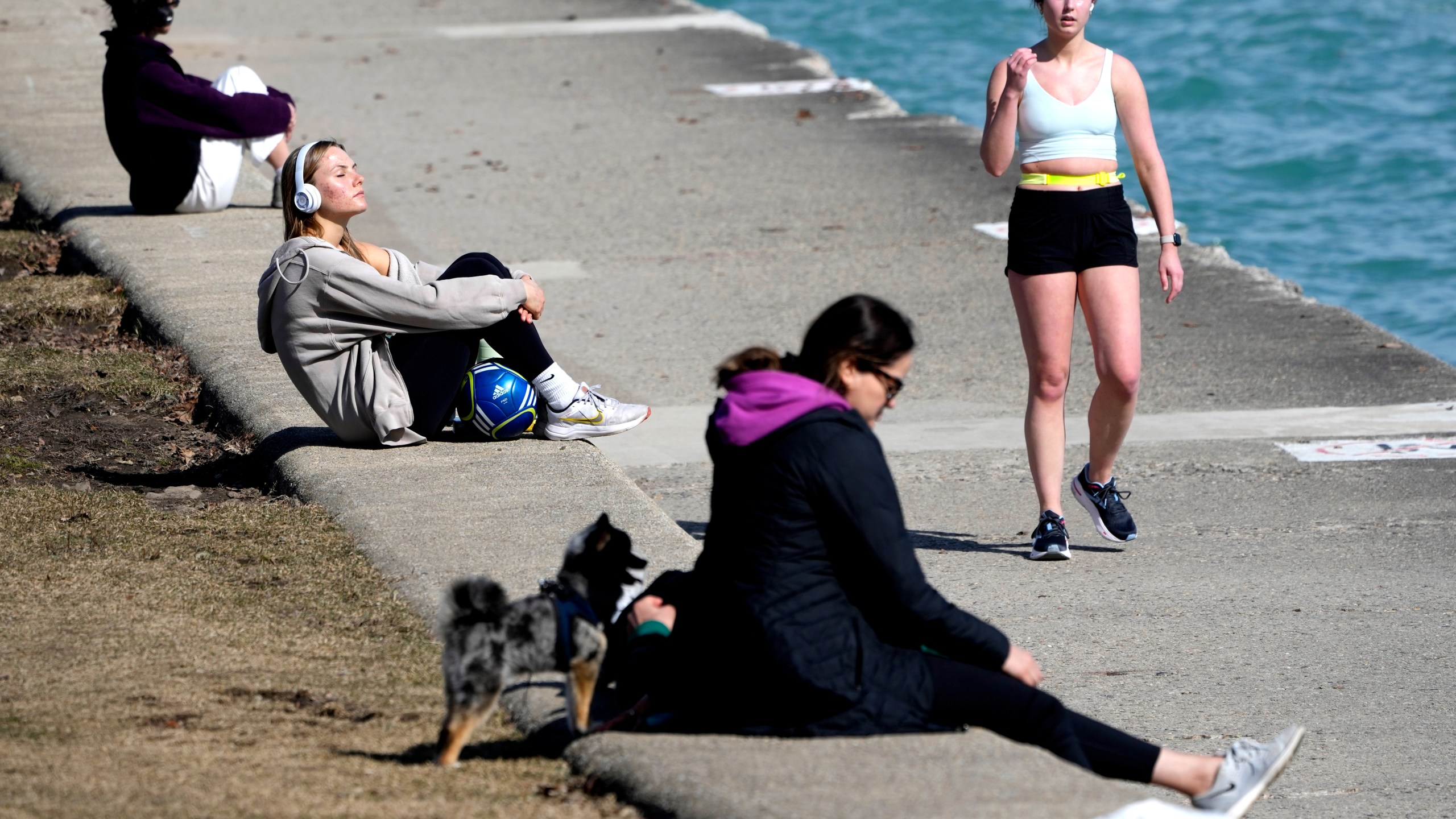 Pedestrians take in the warmer than normal temperatures near the North Avenue Beach Pier along Lake Michigan Monday, Feb. 26, 2024, in Chicago. A warm front is sweeping spring-like weather across a large swath of the country in what is usually one of the coldest months of the year. The rare warmup is sending people out of their homes to enjoy the winter respite but also bringing increased wildfire danger. (AP Photo/Charles Rex Arbogast)