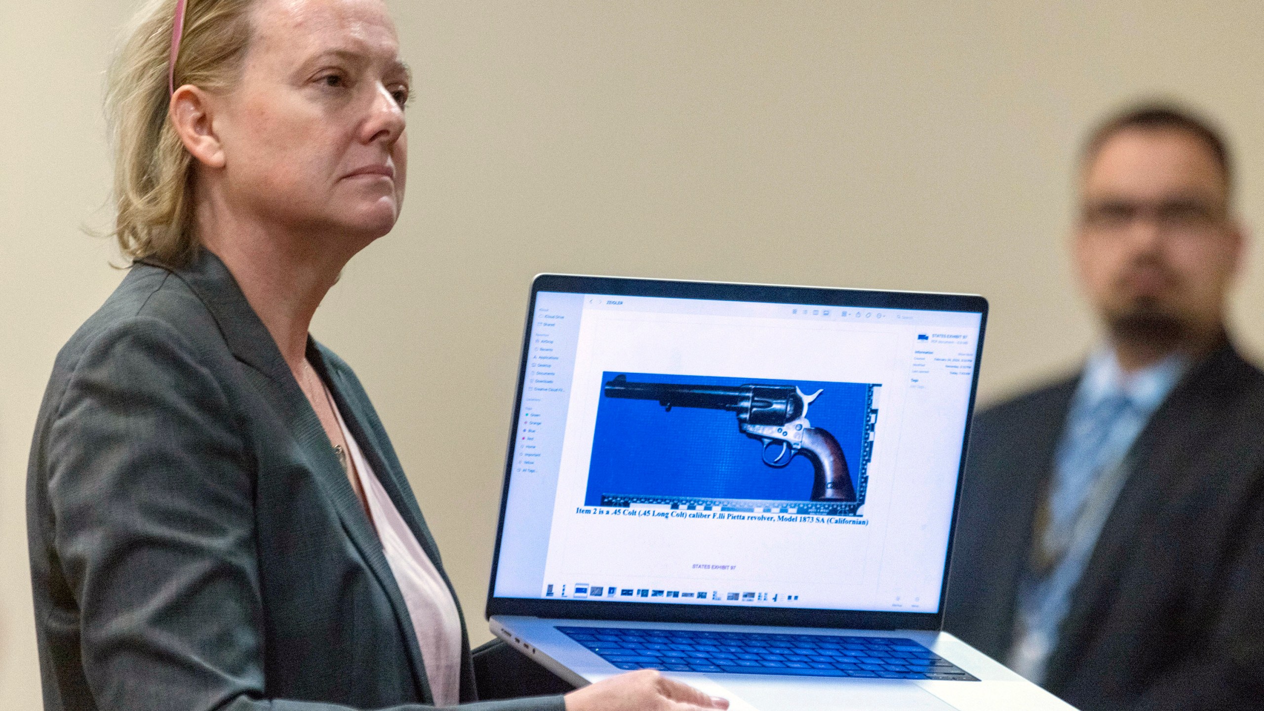 CORRECTION: REMOVES REFERENCE ABOUT OWNERSHIP OF GUN - Special prosecutor Kari Morrissey shows defense attorney Jason Bowles a picture of a firearmReed during Hannah Gutierrez-Reed trial at District Court, Monday, Feb. 26, 2024, in Santa Fe, N.M. Gutierrez-Reed is charged with involuntary manslaughter and tampering with evidence in the October 2021 death of cinematographer Halyna Hutchins during the filming of the Western “Rust”. (Luis Sánchez Saturno/Santa Fe New Mexican via AP, Pool)