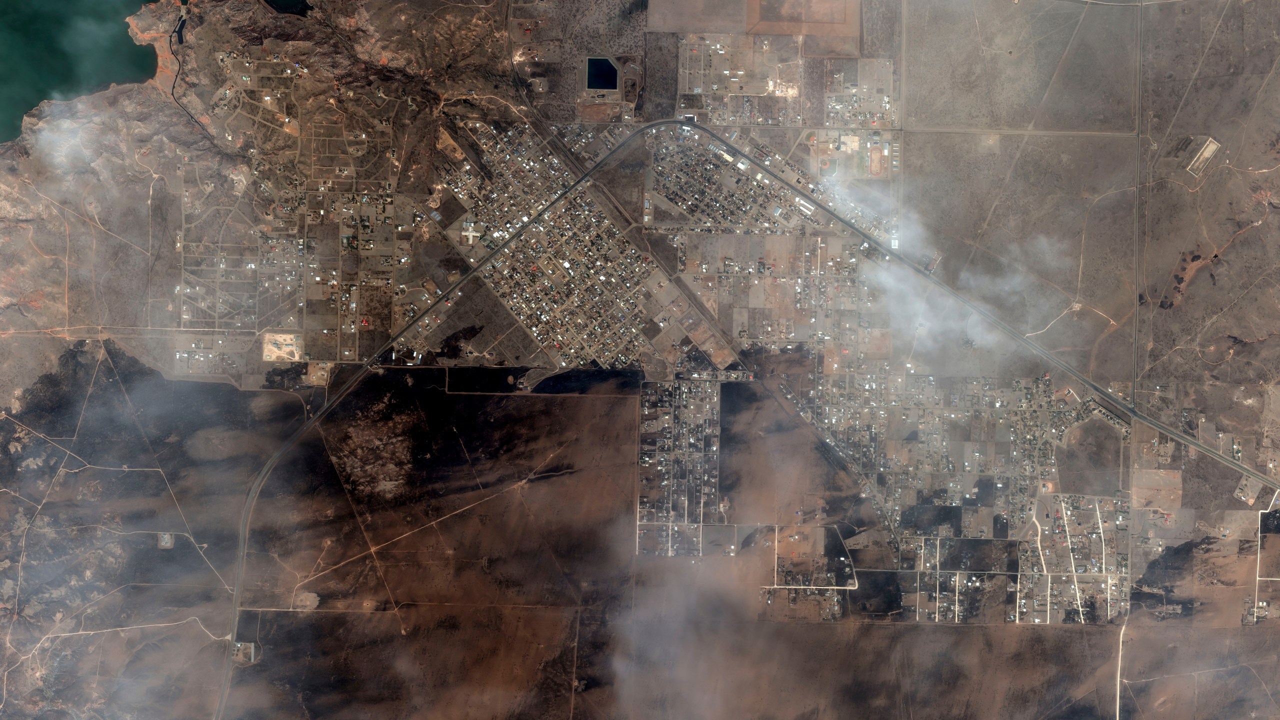 This satellite image provided by Maxar Technologies shows an overview of burned areas with clouds above after the wildfires in the town of Fritch, Texas, Wednesday, Feb. 28, 2024. A cluster of wildfires is scorching the Texas Panhandle, including a blaze that grew into one of the largest in state history. The flames blackened the landscape across a vast stretch of small towns and cattle ranches. (Maxar Technologies via AP)