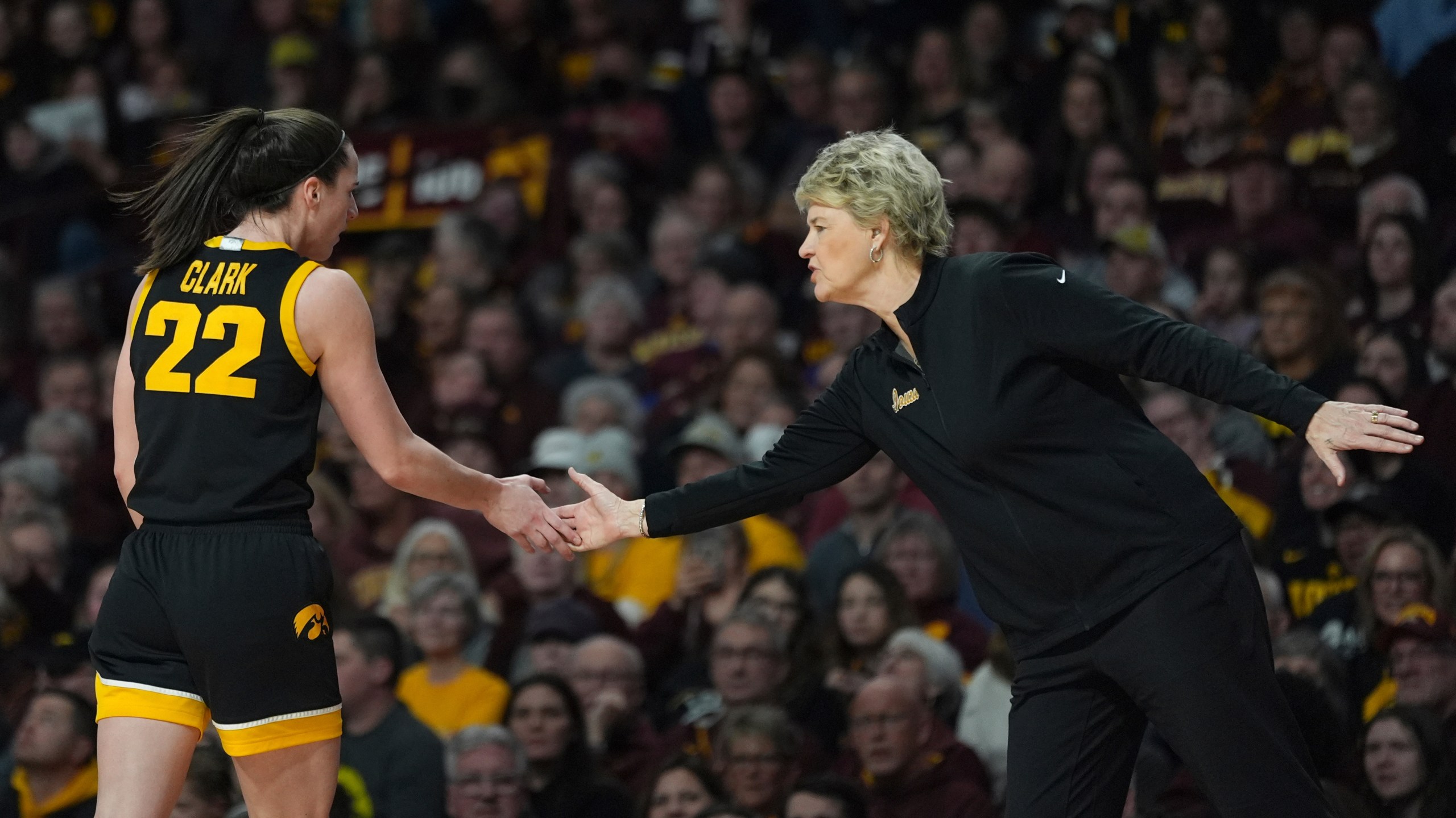 Iowa guard Caitlin Clark (22) and head coach Lisa Bluder high-five during the first half of an NCAA college basketball game against Minnesota, Wednesday, Feb. 28, 2024, in Minneapolis. (AP Photo/Abbie Parr)